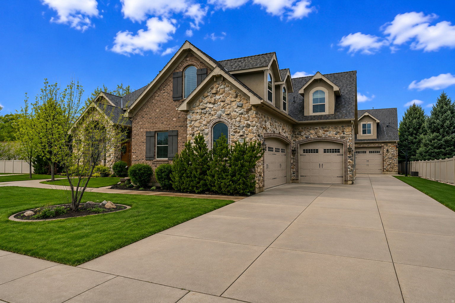 Stone and brick-clad exterior with dormer windows, shuttered windows, and multiple attached garage bays