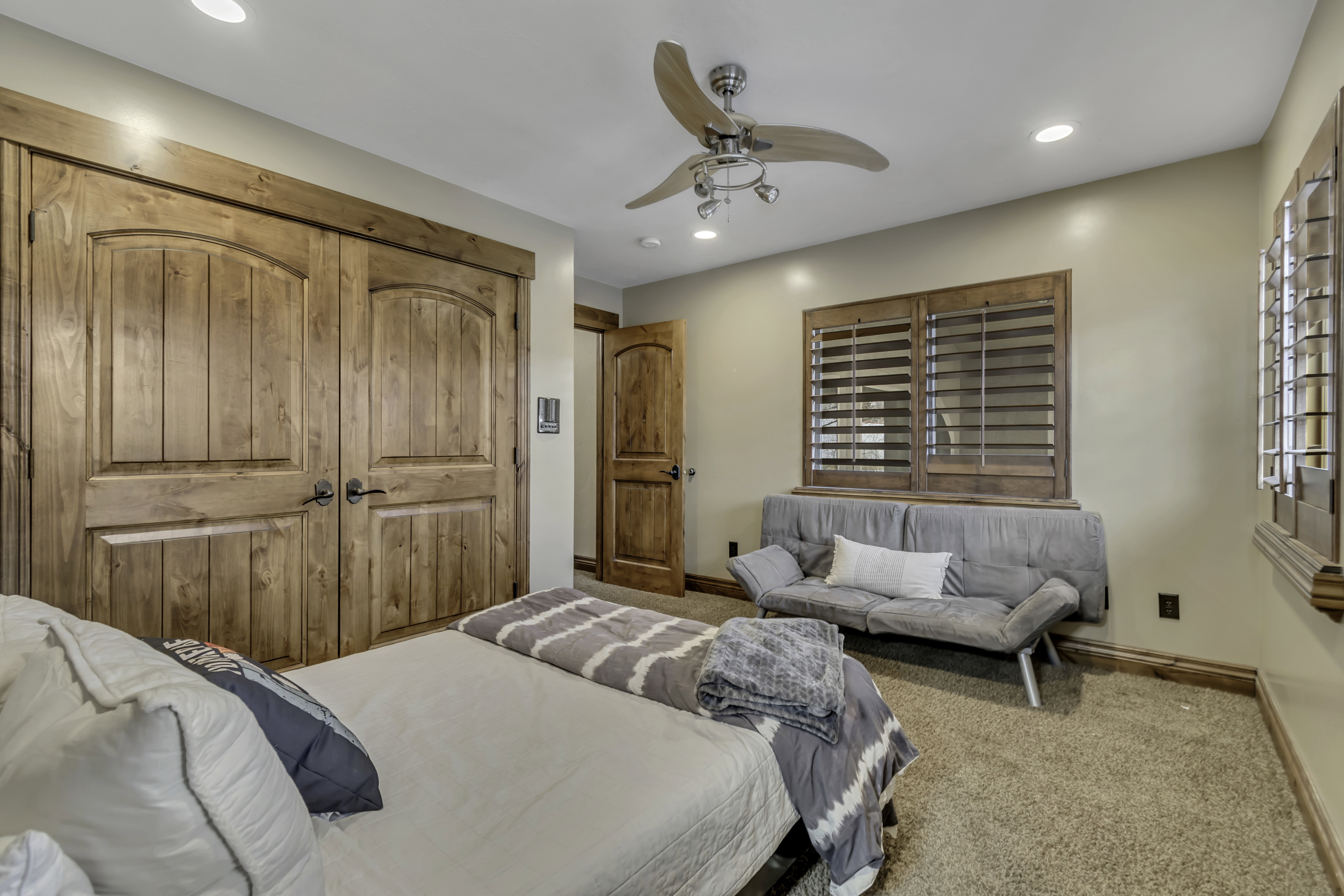 Room featuring wood-finish arched panel doors, recessed lighting, a ceiling fan with integrated lighting, and wood-finish interior window shutters