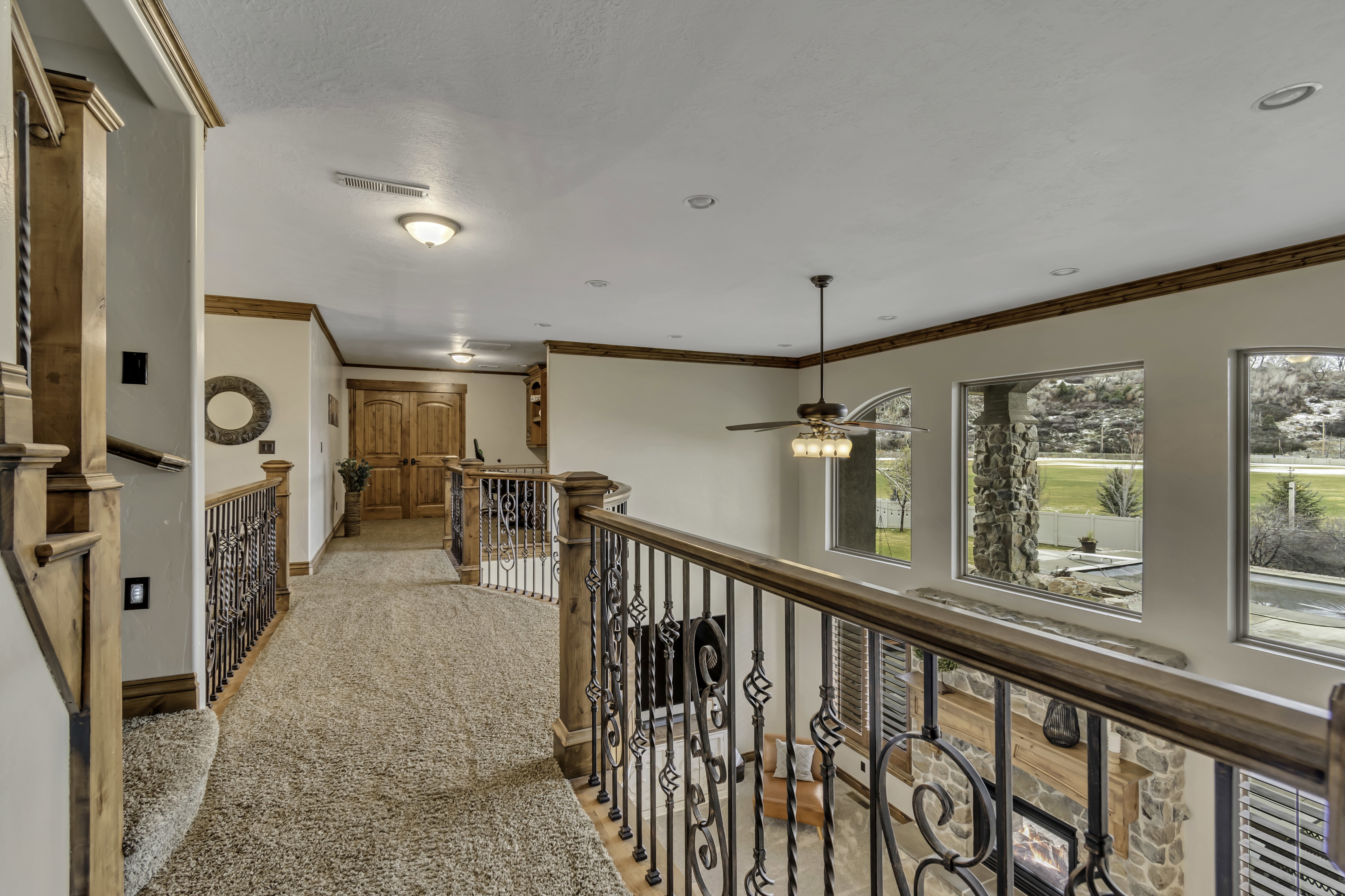 Upper-level hallway featuring wood-finish handrails and decorative wrought iron balusters