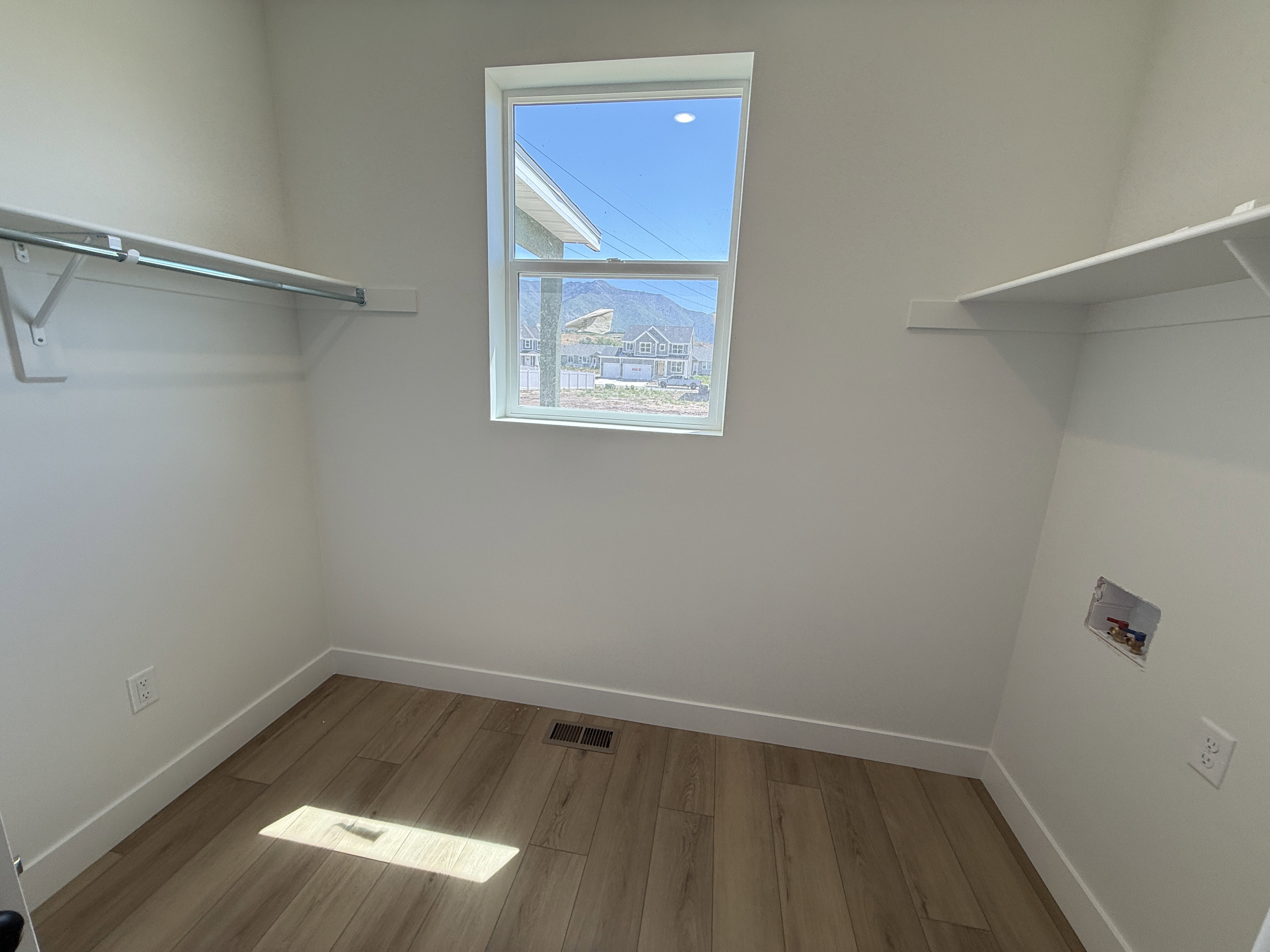 Utility space featuring wood-finish flooring, a single window, and white walls