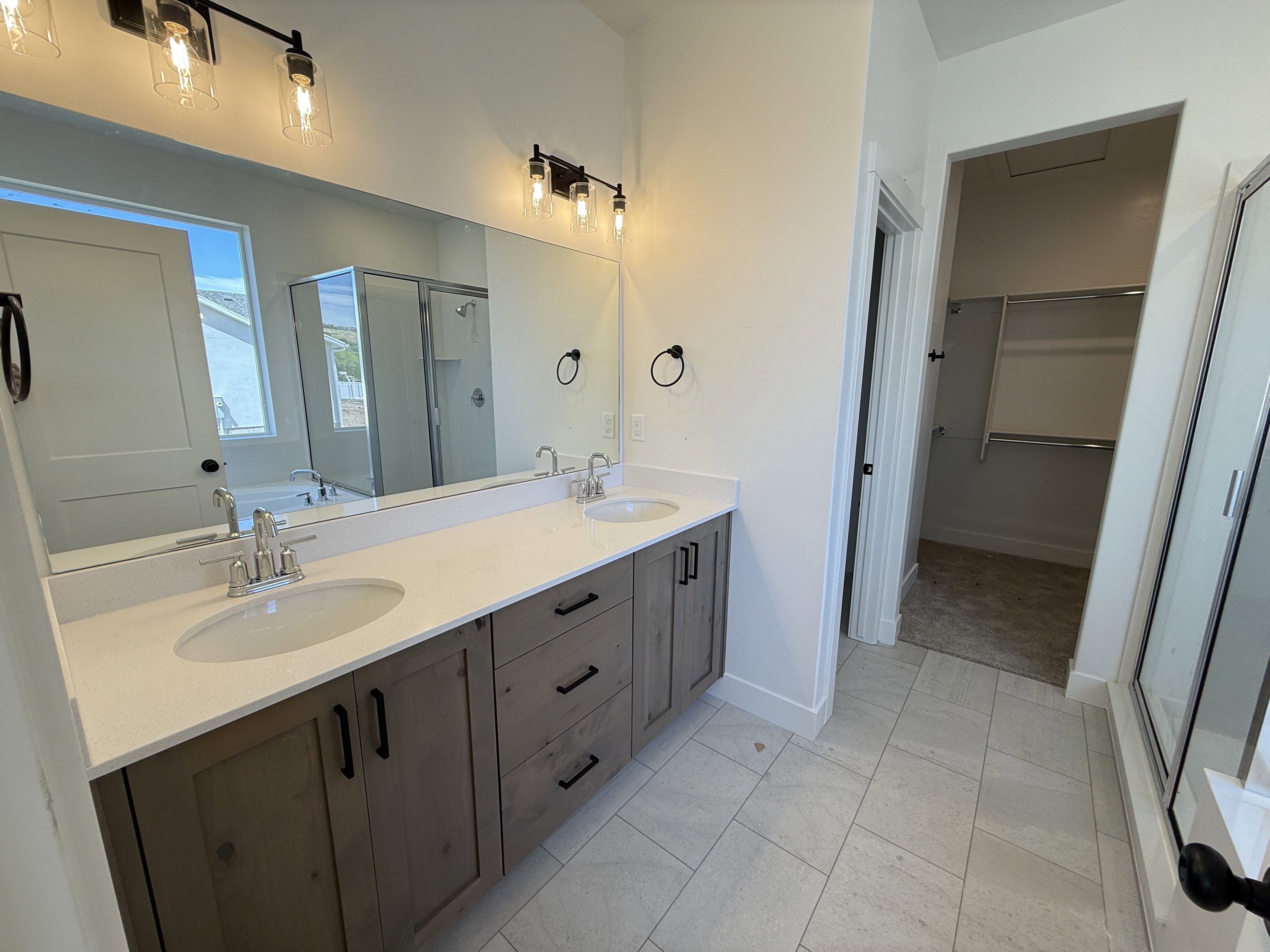 Double vanity with white solid surface countertop, undermount sinks, and wood-finish cabinetry