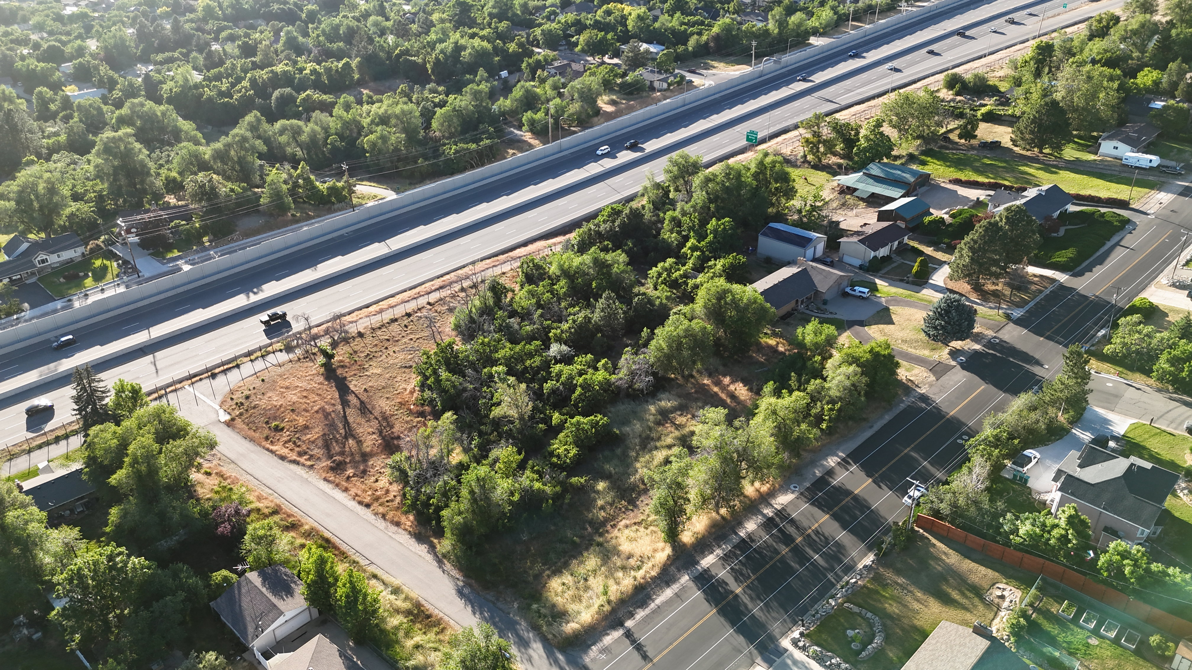 Aerial perspective showcasing a major transportation corridor, surrounding residential areas, and abundant mature trees