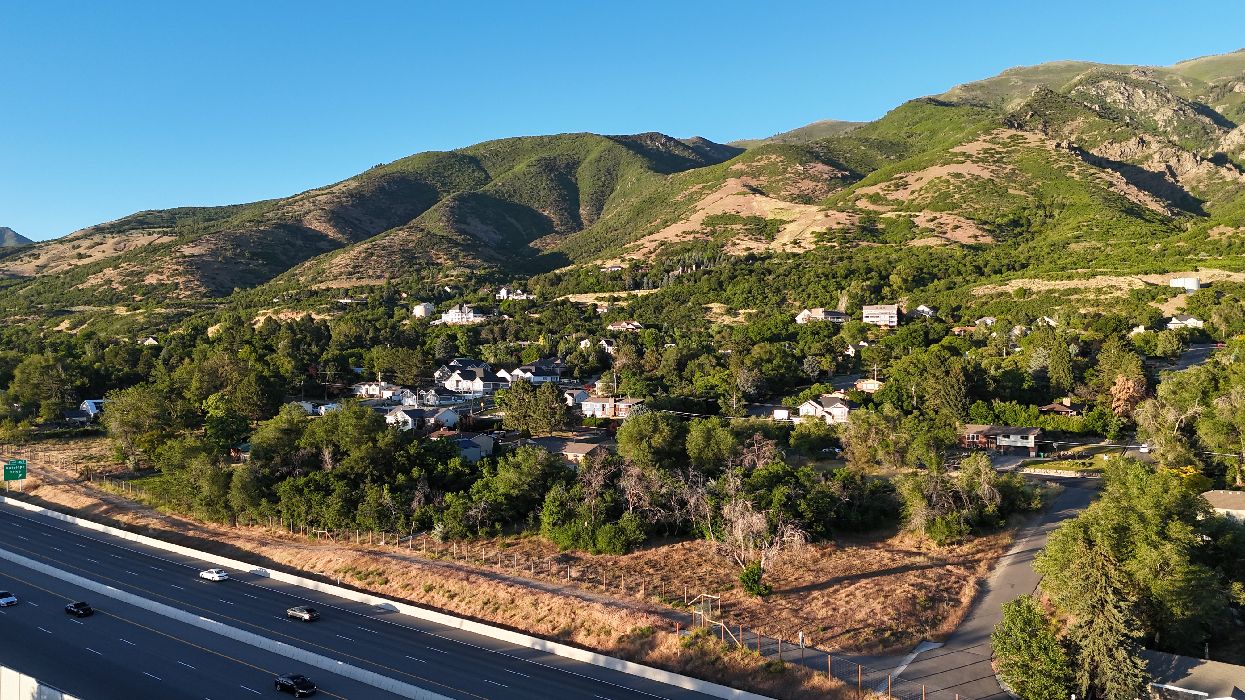 Mountainous terrain and lush green vegetation form a natural backdrop for the residential area