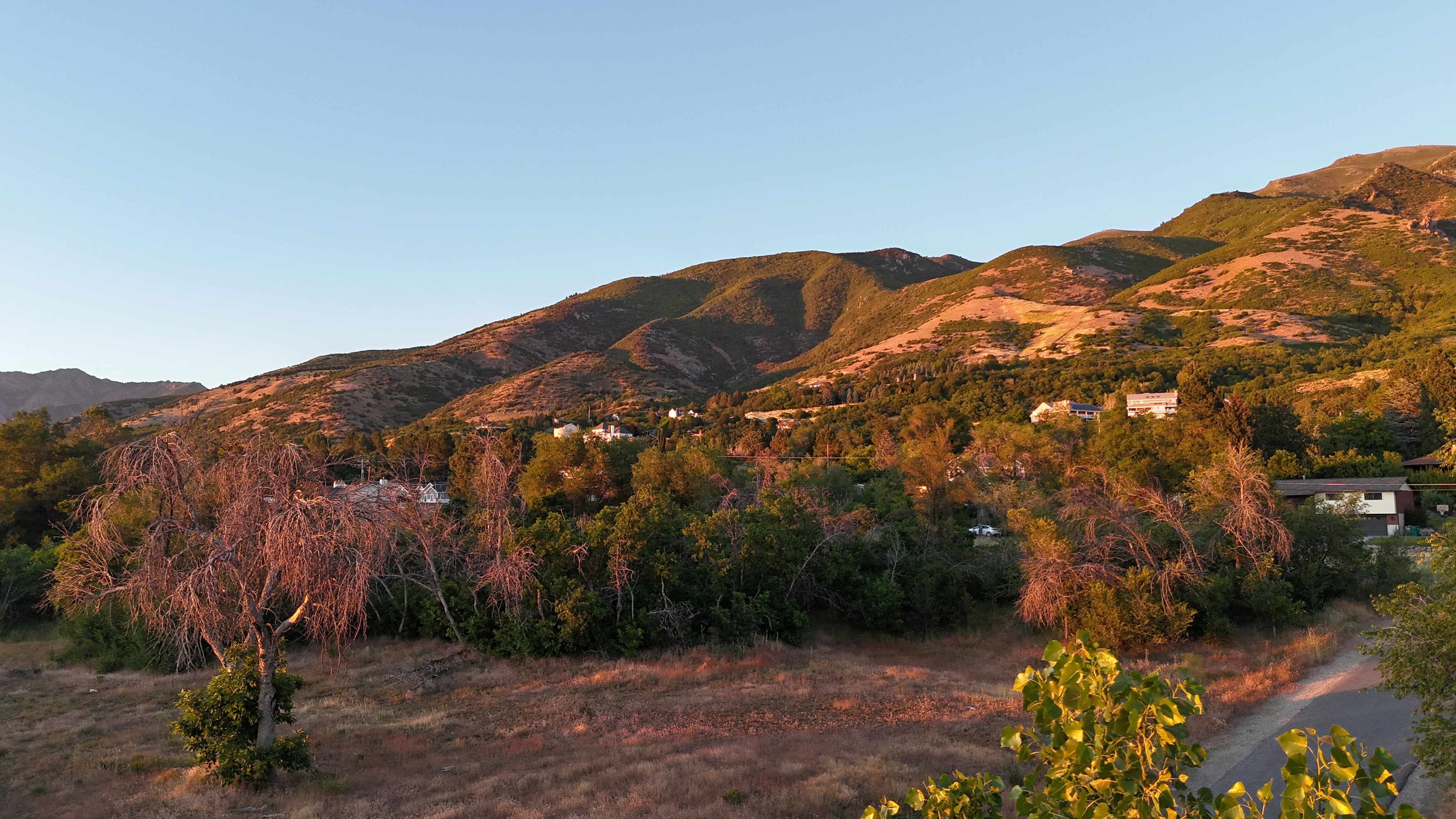 Sweeping mountain landscape featuring natural foliage and distant residential structures