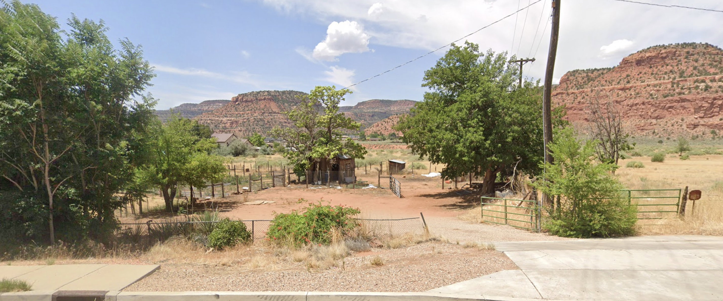Expansive open land featuring a gravel driveway and partial fencing