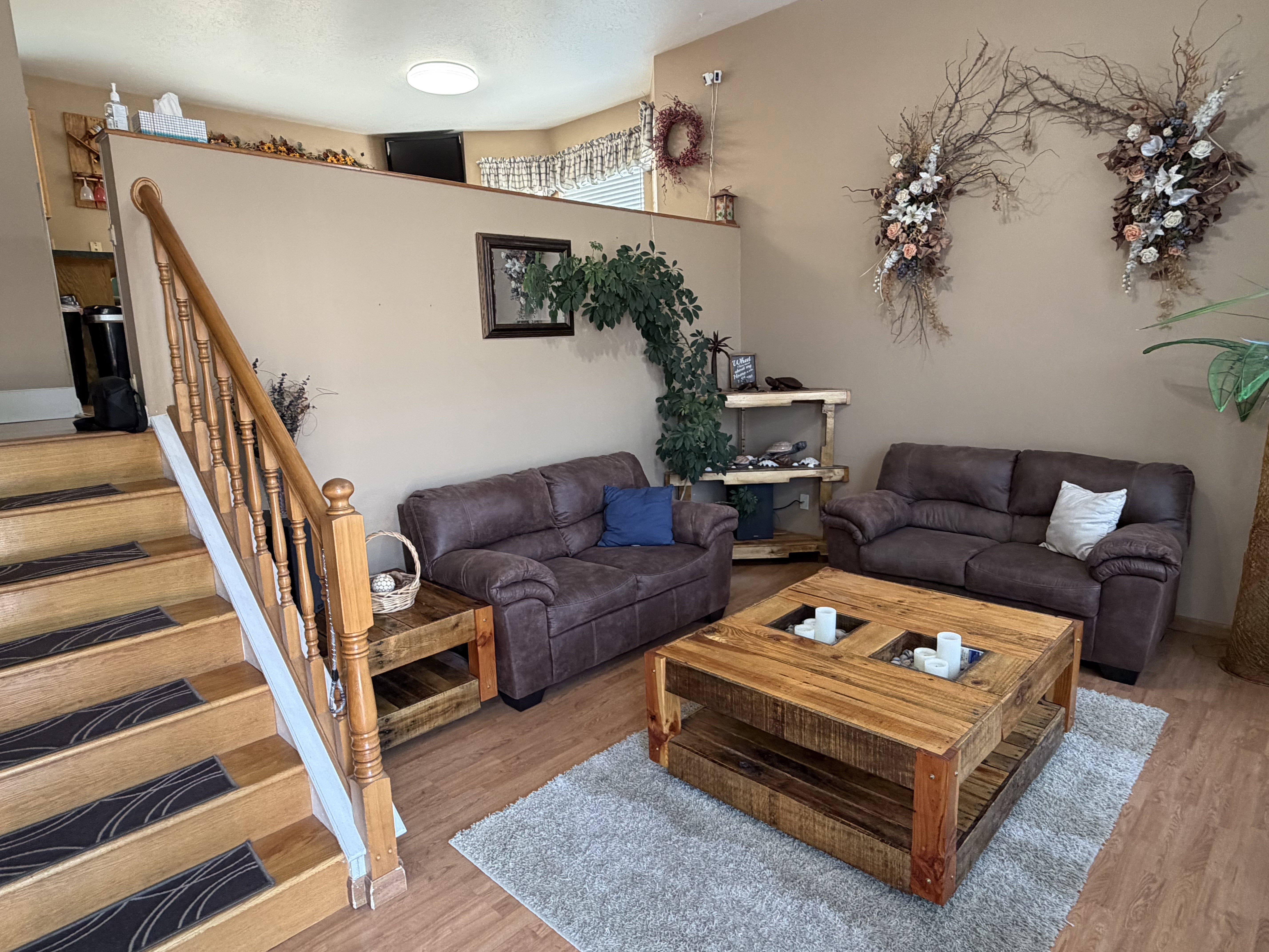 Warm living area featuring wood-finish flooring and a central staircase with a wood balustrade