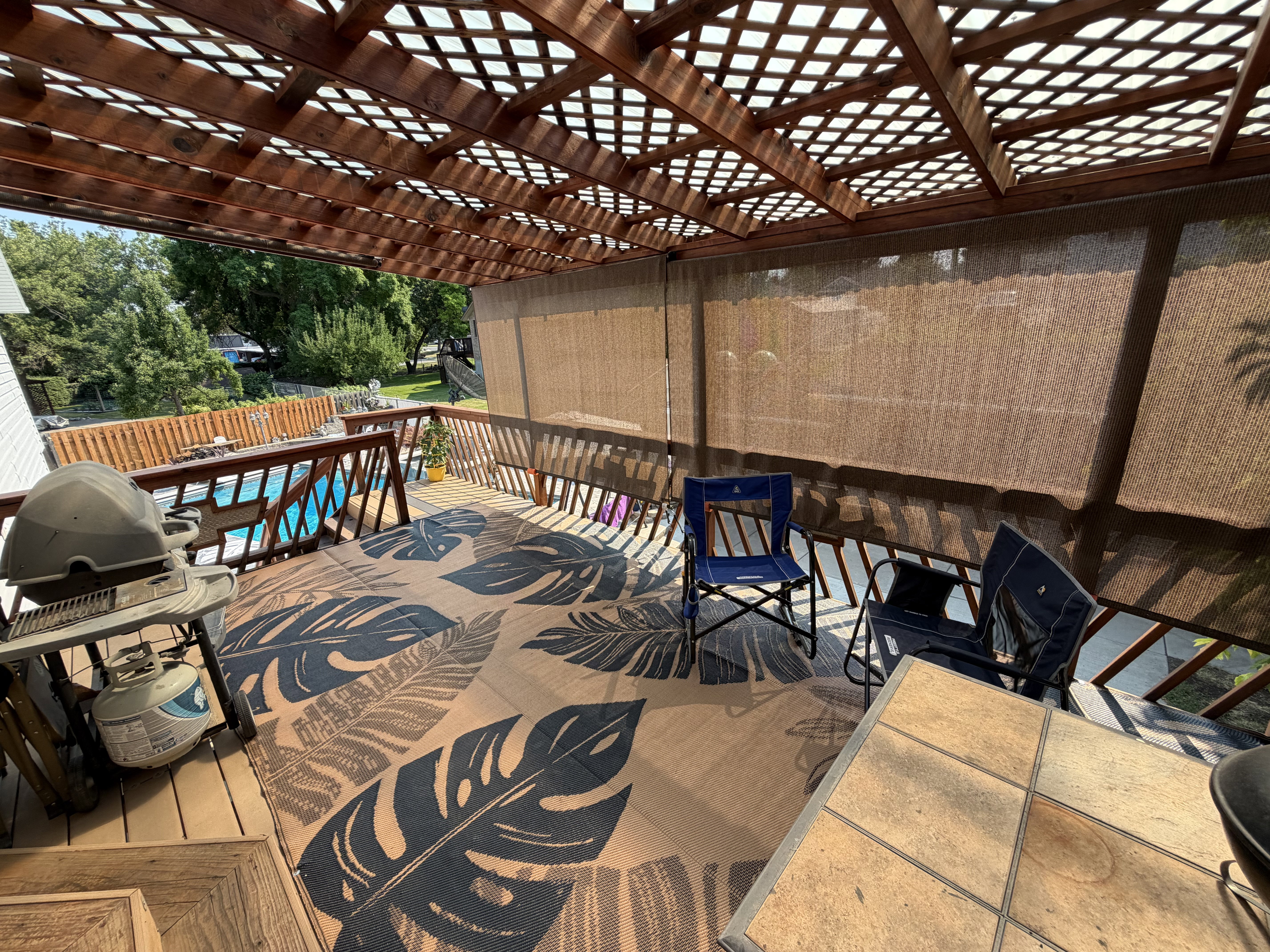 Expansive deck with wood-finish flooring, featuring a lattice-style pergola overhead