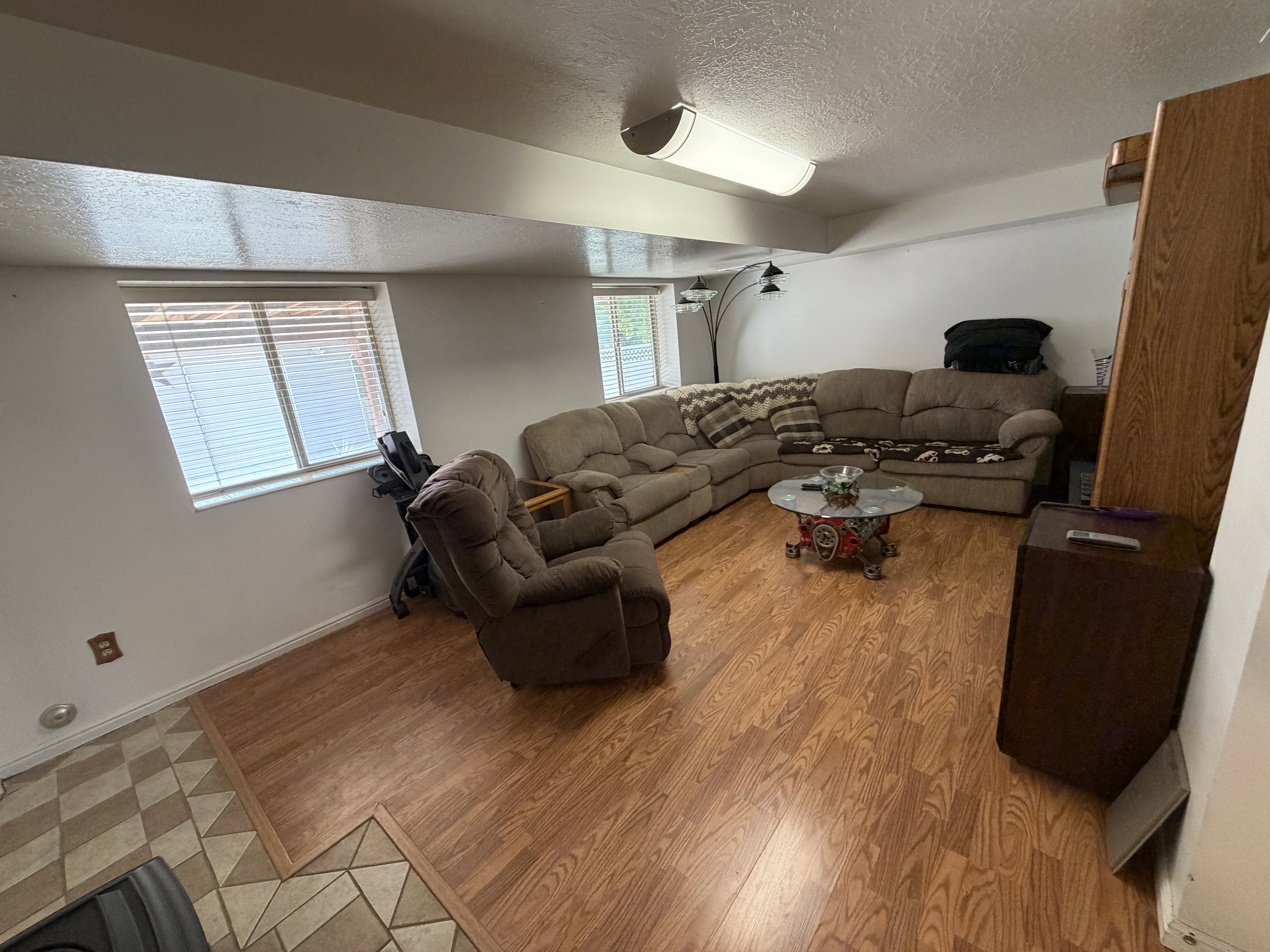 Spacious room featuring wood-finish flooring, white walls, and a dropped ceiling with integrated lighting