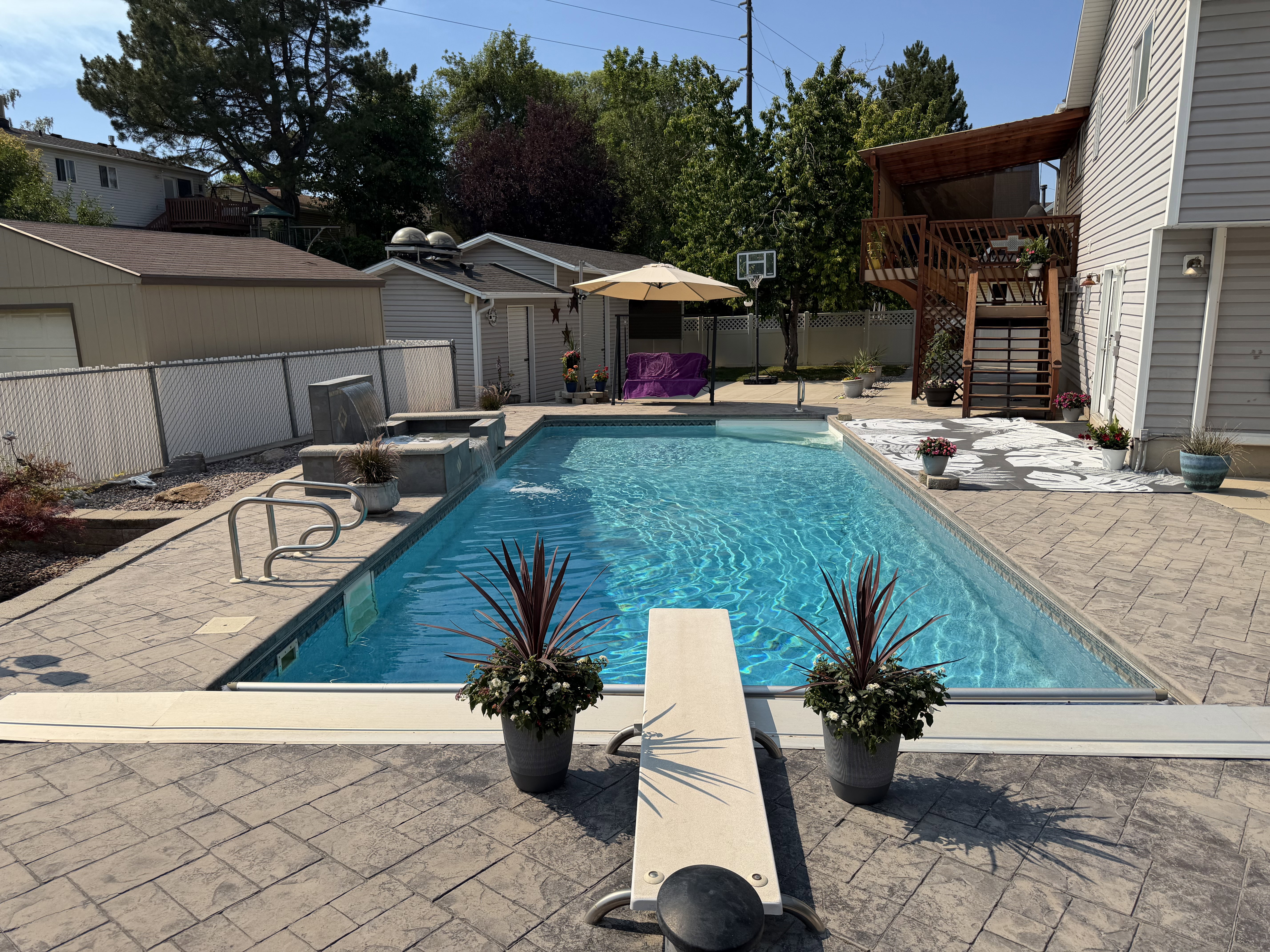 Rectangular swimming pool with a diving board, surrounded by stamped concrete decking