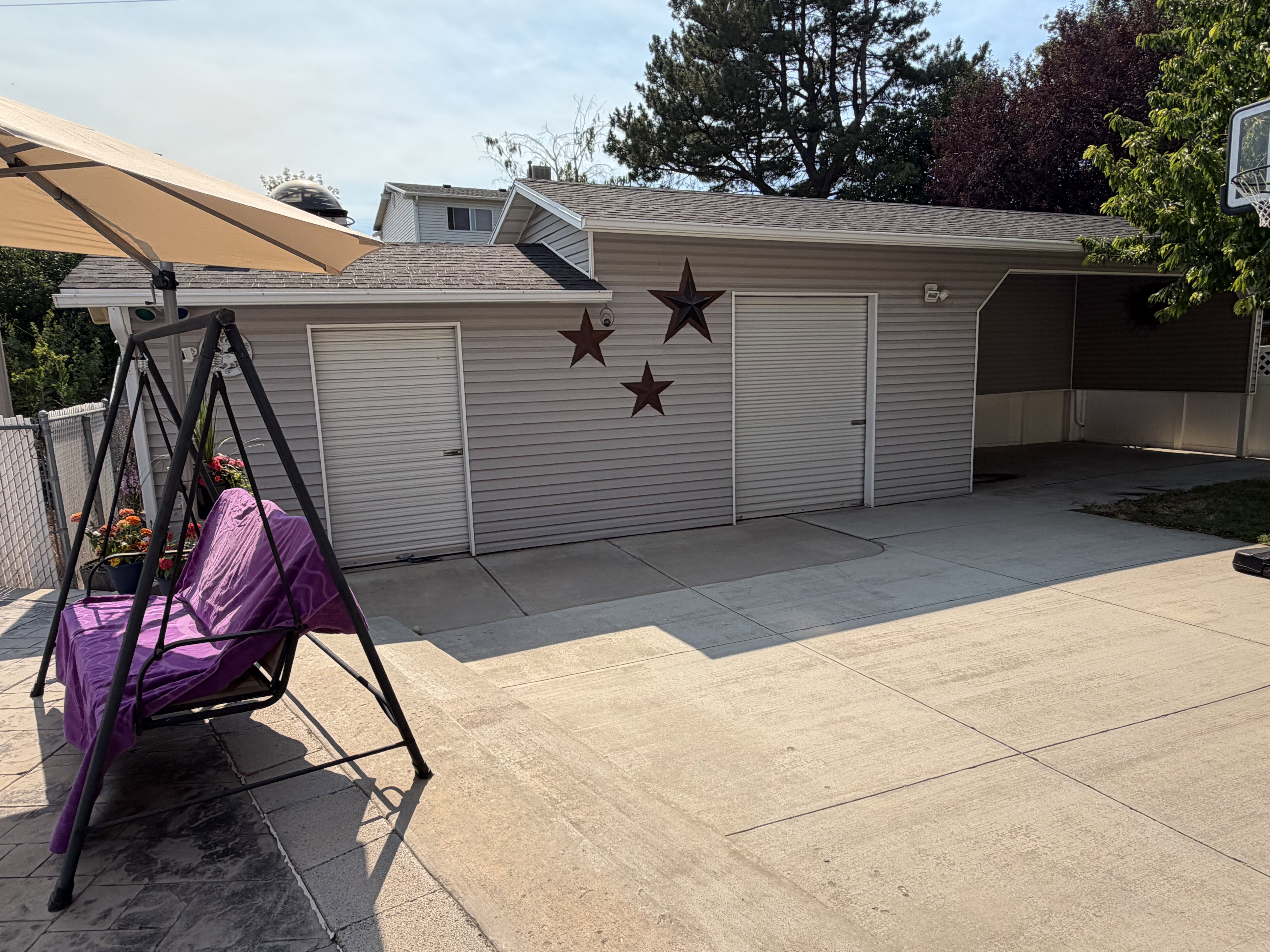 Detached garage with two roll-up doors, an additional service door, and an attached covered carport