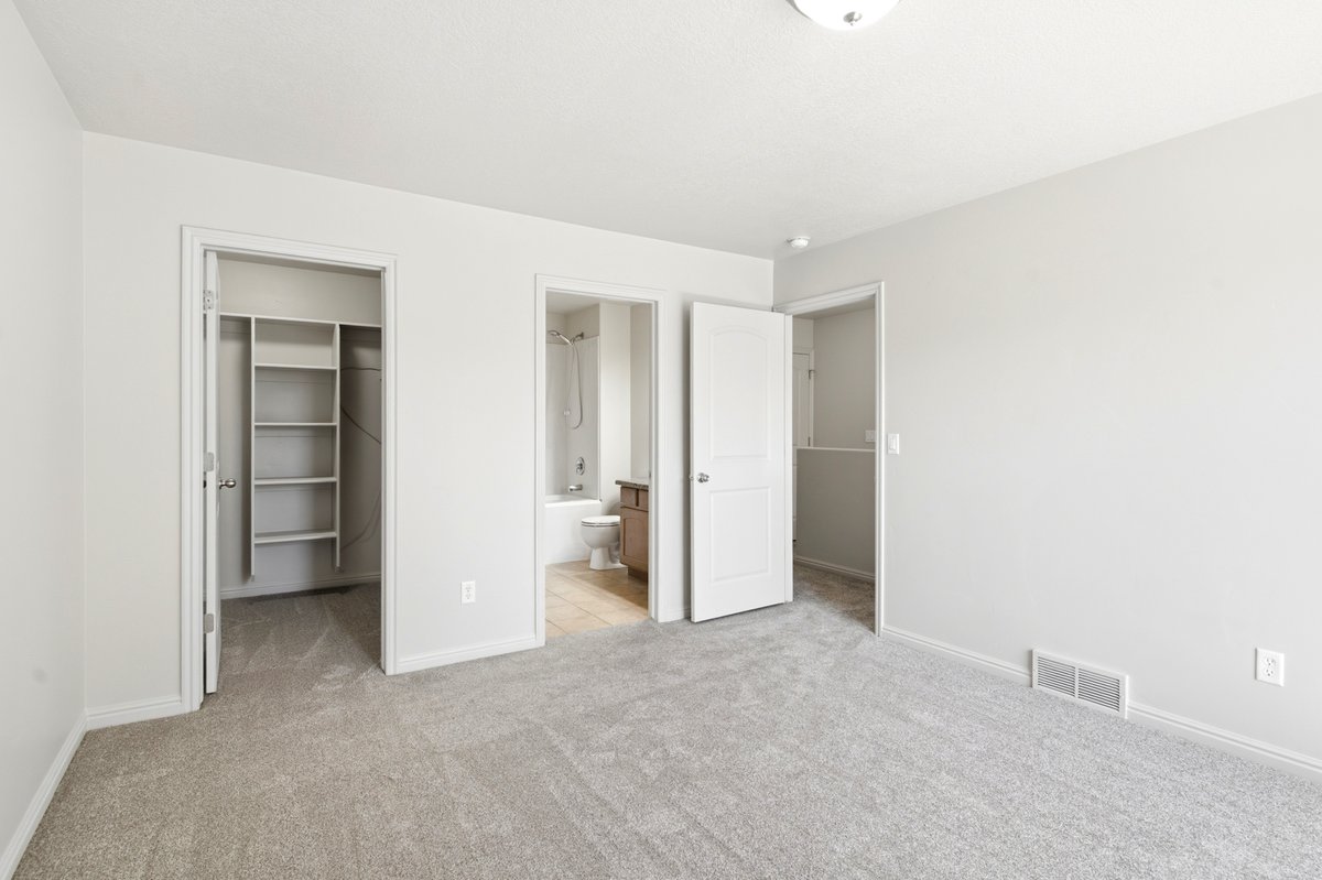 Spacious carpeted room featuring a ceiling light fixture, white trim, and light gray walls
