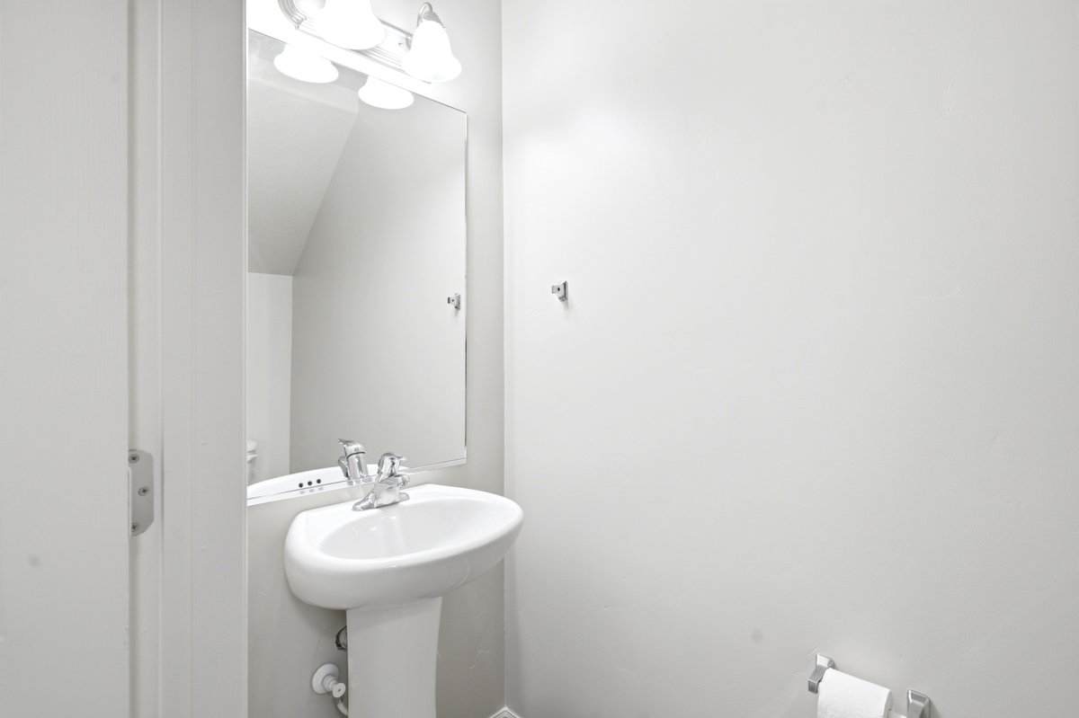 Pedestal sink with chrome faucet, large vanity mirror, and three-light fixture