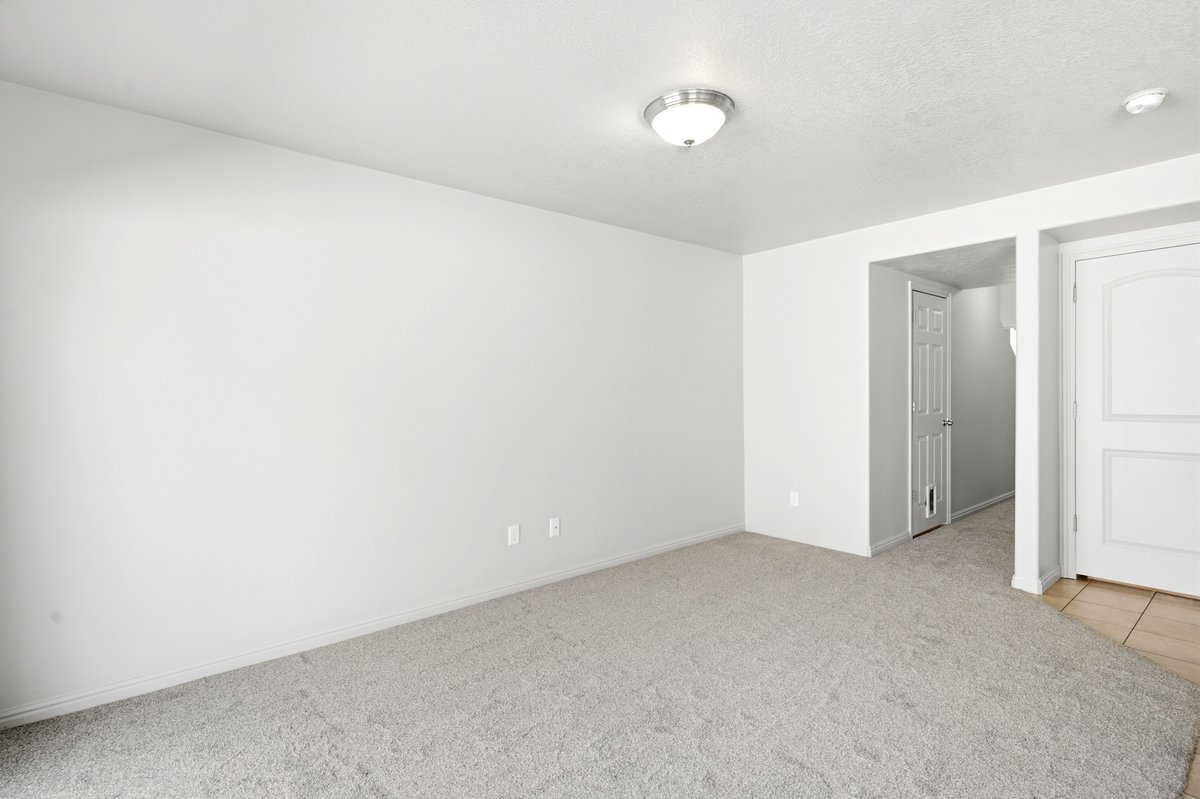 Open-concept room featuring light gray carpeting, white painted walls, a flush-mount ceiling light fixture, and white baseboards