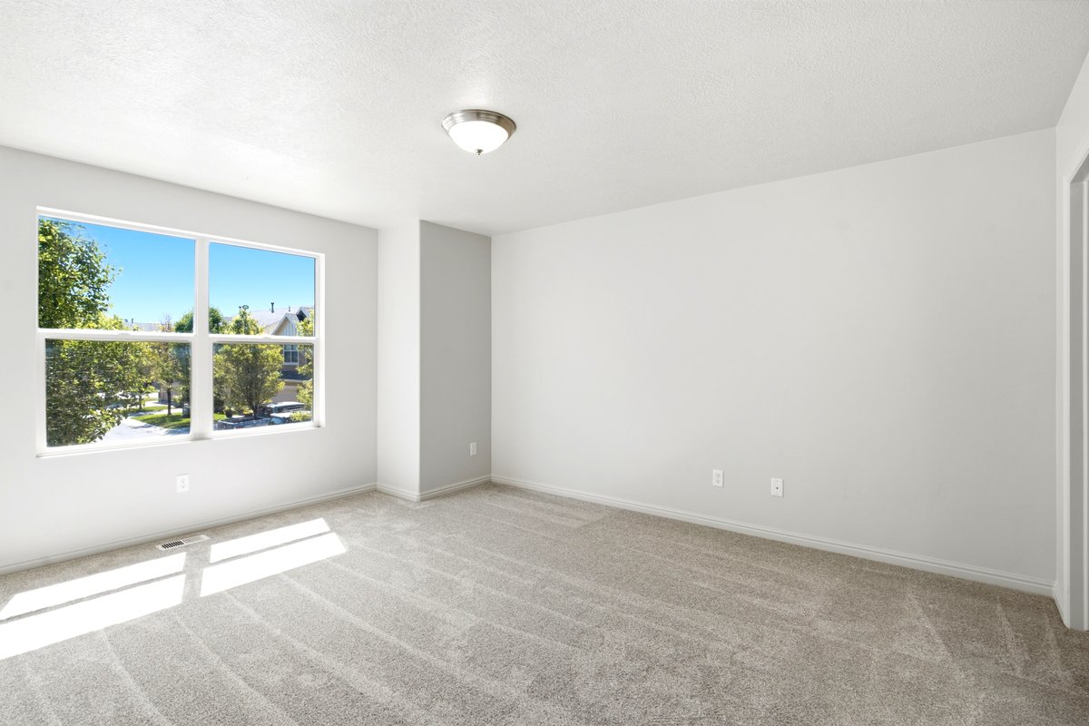 Spacious room featuring a large window, light gray carpeting, and a flush-mount ceiling light fixture