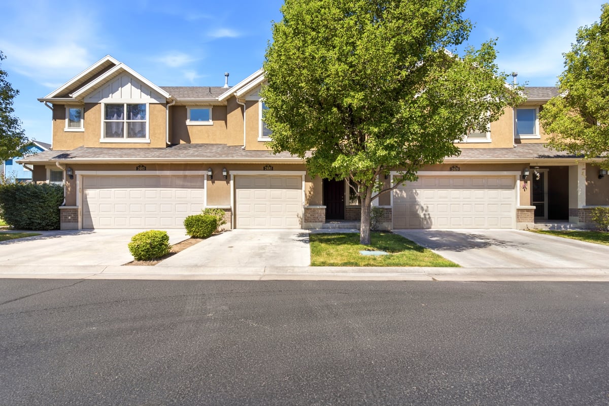 Contemporary townhome exterior featuring stucco siding, stone accents, and multiple garage doors