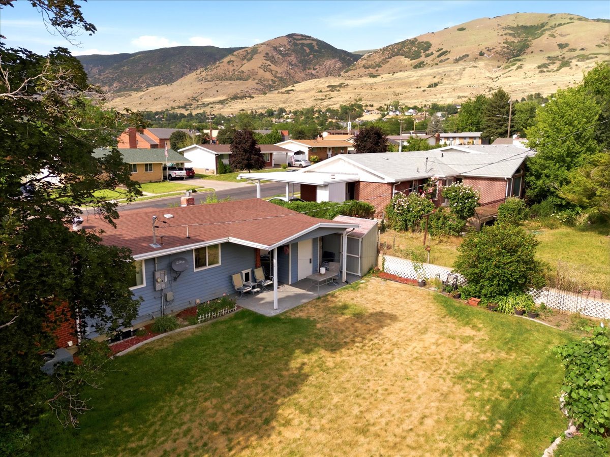 Sweet (not too large, but just right) backyard area with a covered patio, garden beds, and mountain scenery