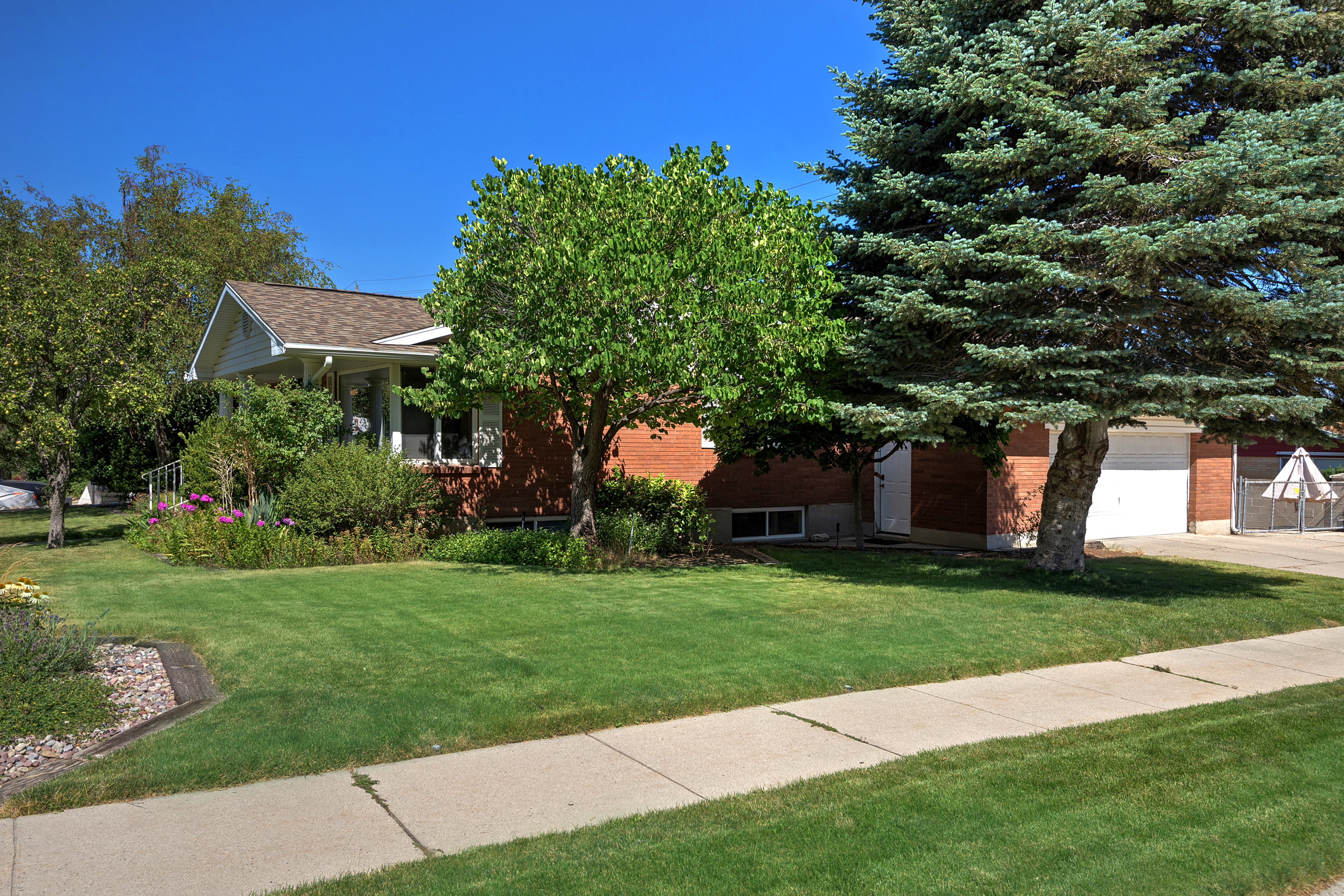 Red brick exterior with a front porch, white garage door, and a concrete sidewalk