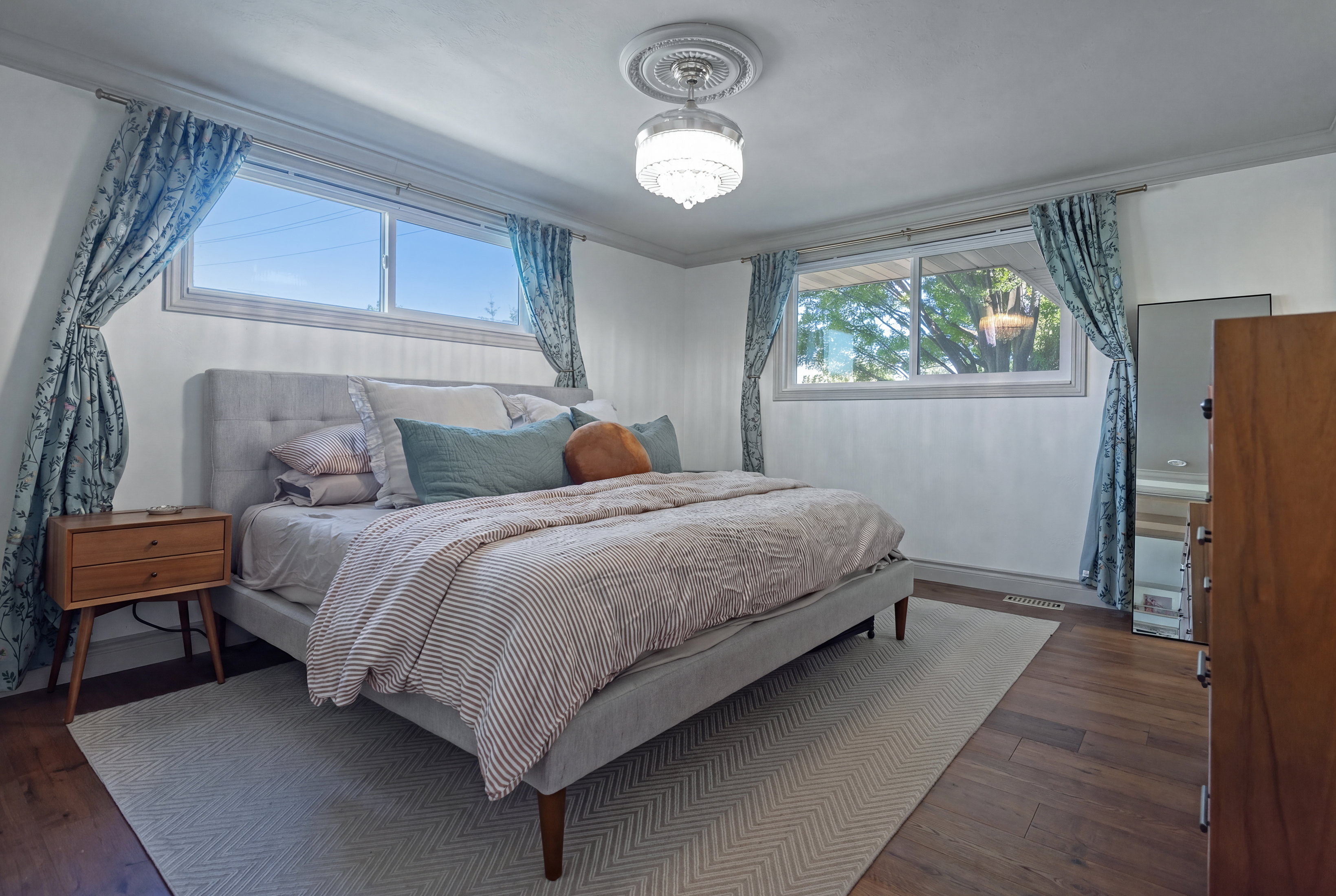 Bedroom featuring wood-finish flooring, white walls, and a decorative ceiling light fixture