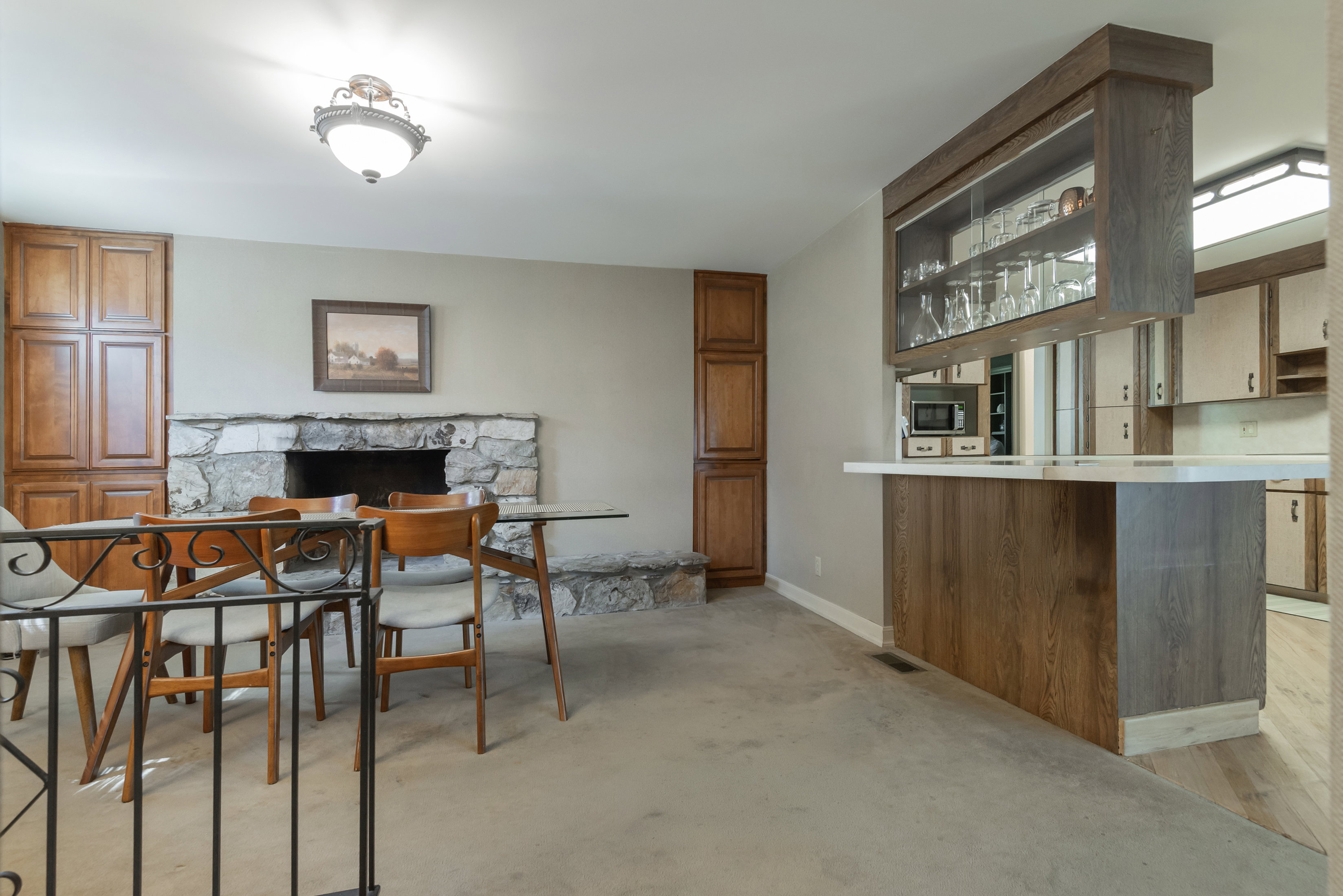 Dining area featuring a stone fireplace with a raised hearth, built-in wood cabinetry, and a dedicated bar space with an overhead display cabinet