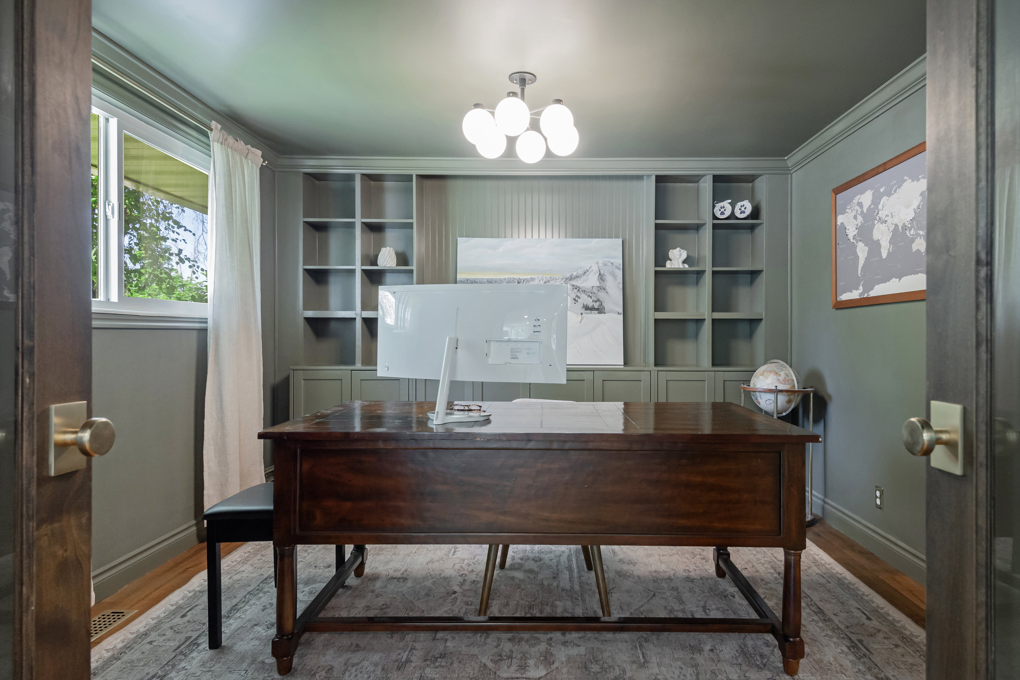 Dedicated room featuring built-in shelving, wood-finish flooring, and a multi-bulb ceiling fixture