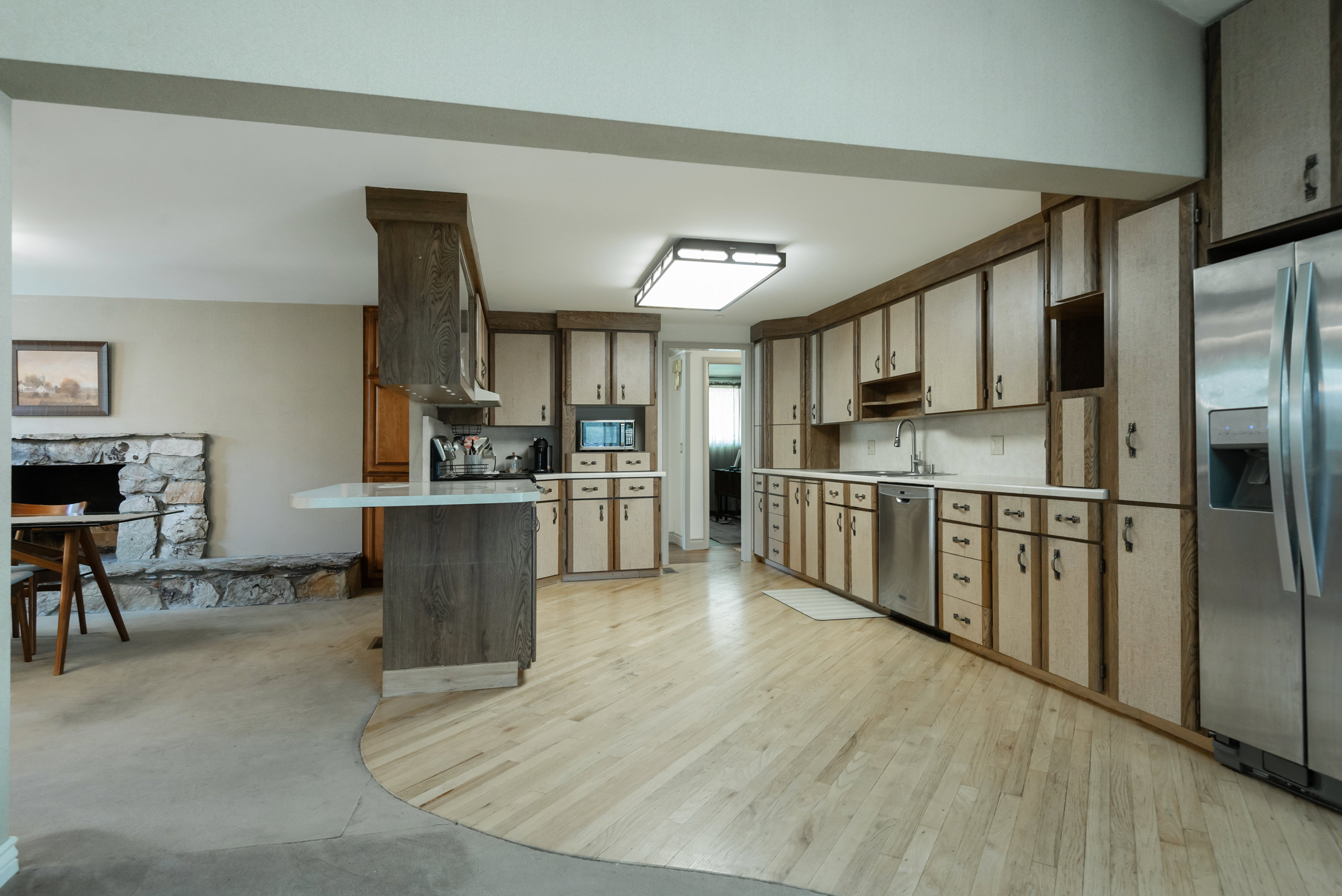 Open-concept kitchen featuring light-toned wood-finish flooring, extensive cabinetry with integrated hardware, and stainless steel appliances