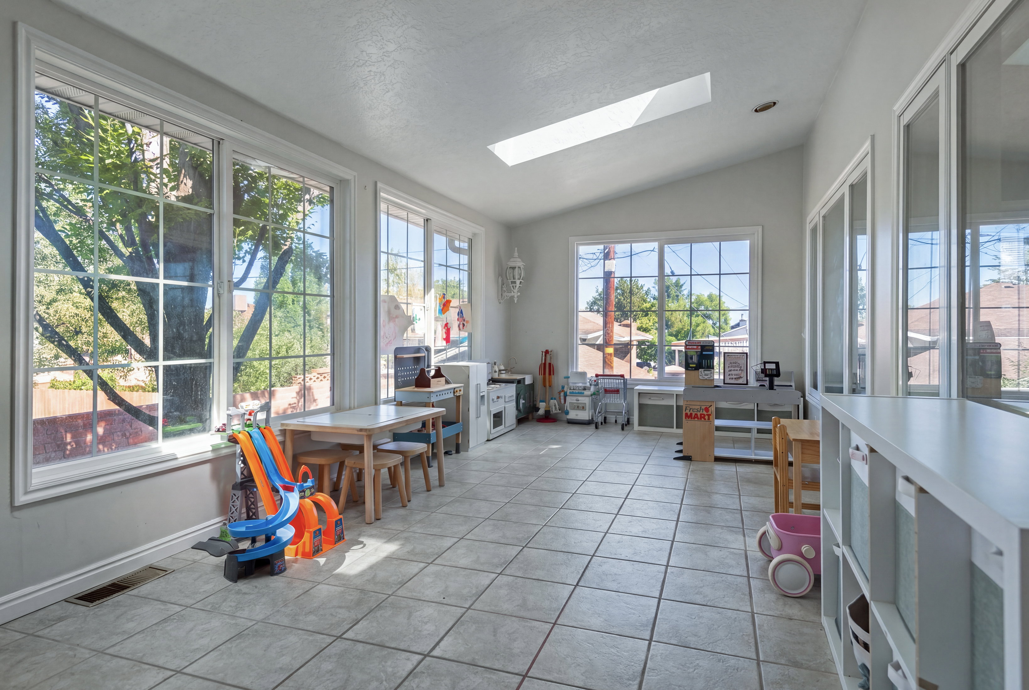 Spacious room featuring multiple large grid-pattern windows, a skylight, and a vaulted ceiling