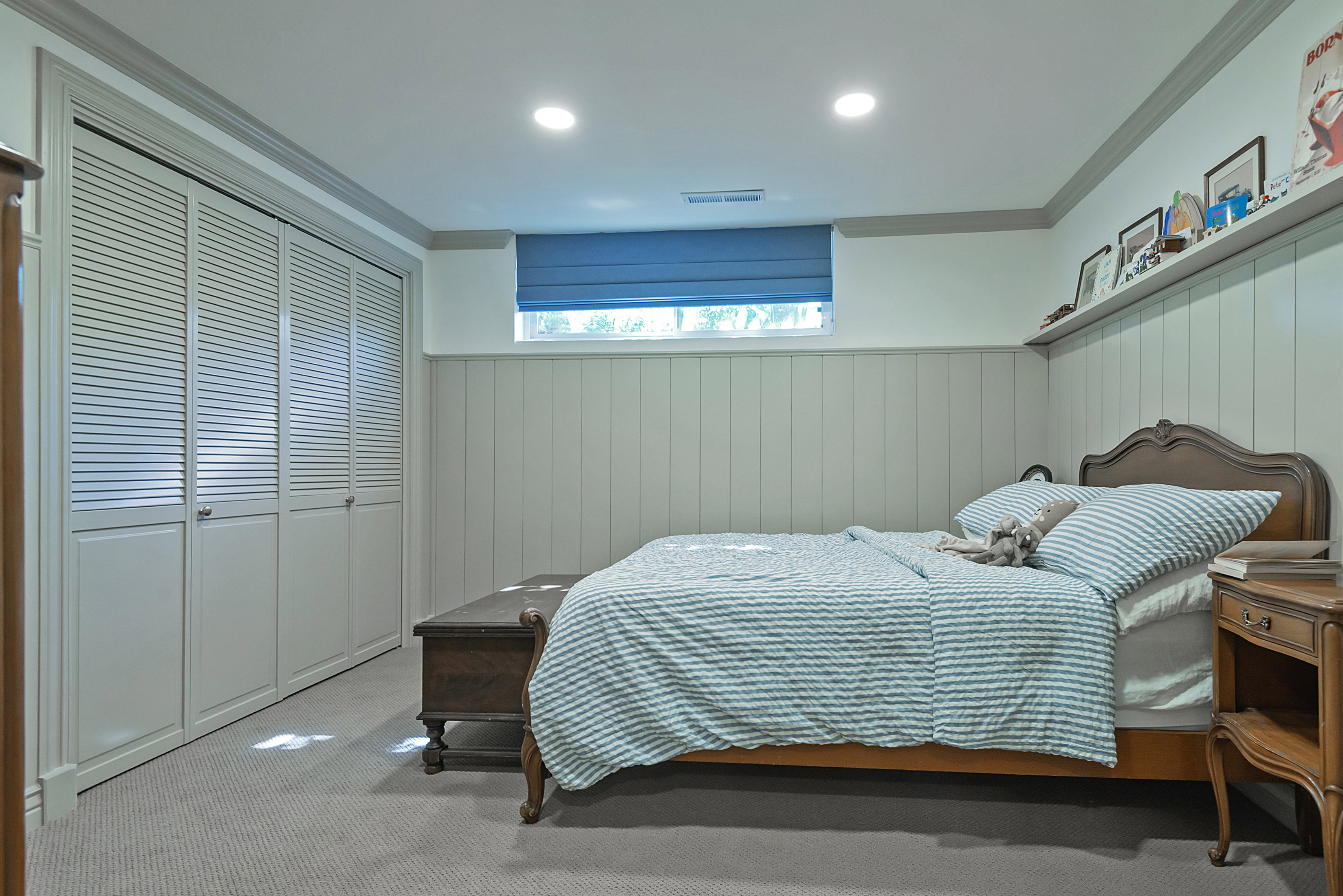 Bedroom featuring board and batten wainscoting, recessed lighting, and a window with a blue roman shade