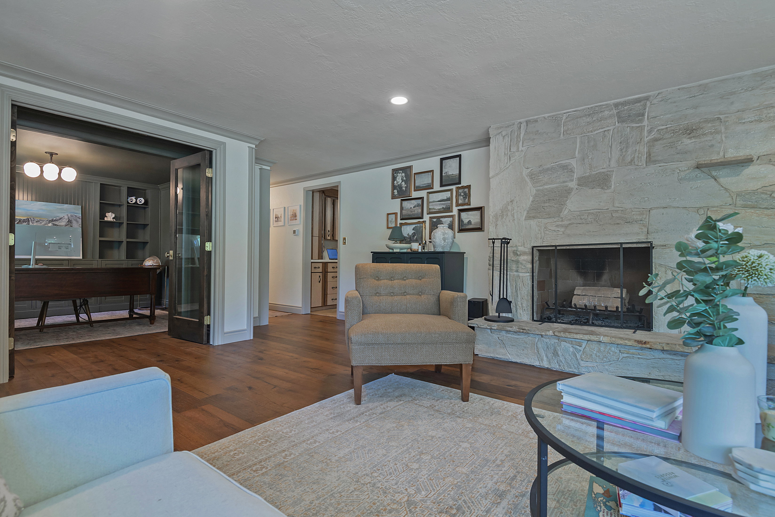 Living area featuring a stone fireplace with hearth, wood-finish flooring, and recessed lighting