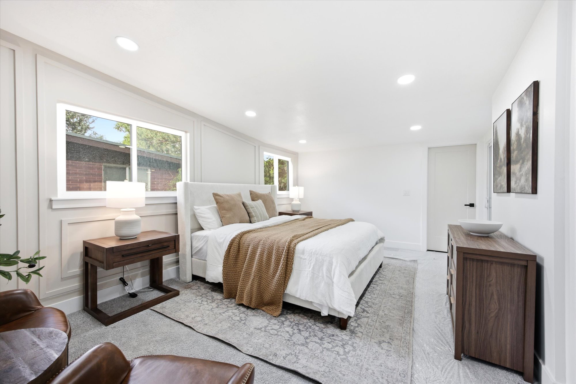 Spacious bedroom featuring recessed lighting, large windows, a white paneled accent wall, wood-finish flooring, and a solid core door