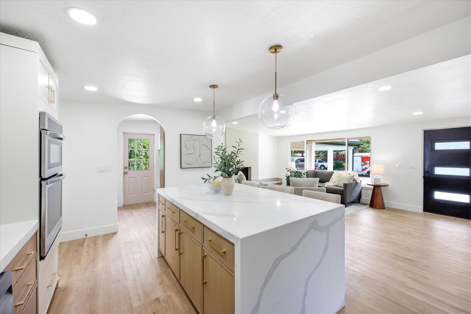Kitchen island featuring a waterfall countertop with veining, under-cabinet storage, and gold-tone hardware