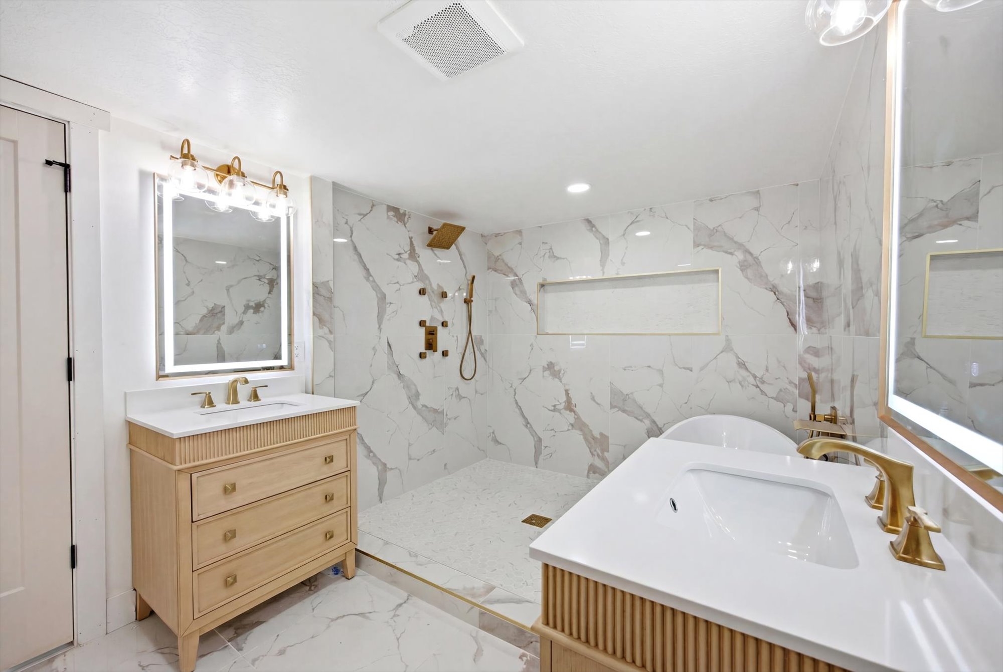 Bathroom featuring dual vanities with integrated sinks, quartz countertops, and brushed gold fixtures