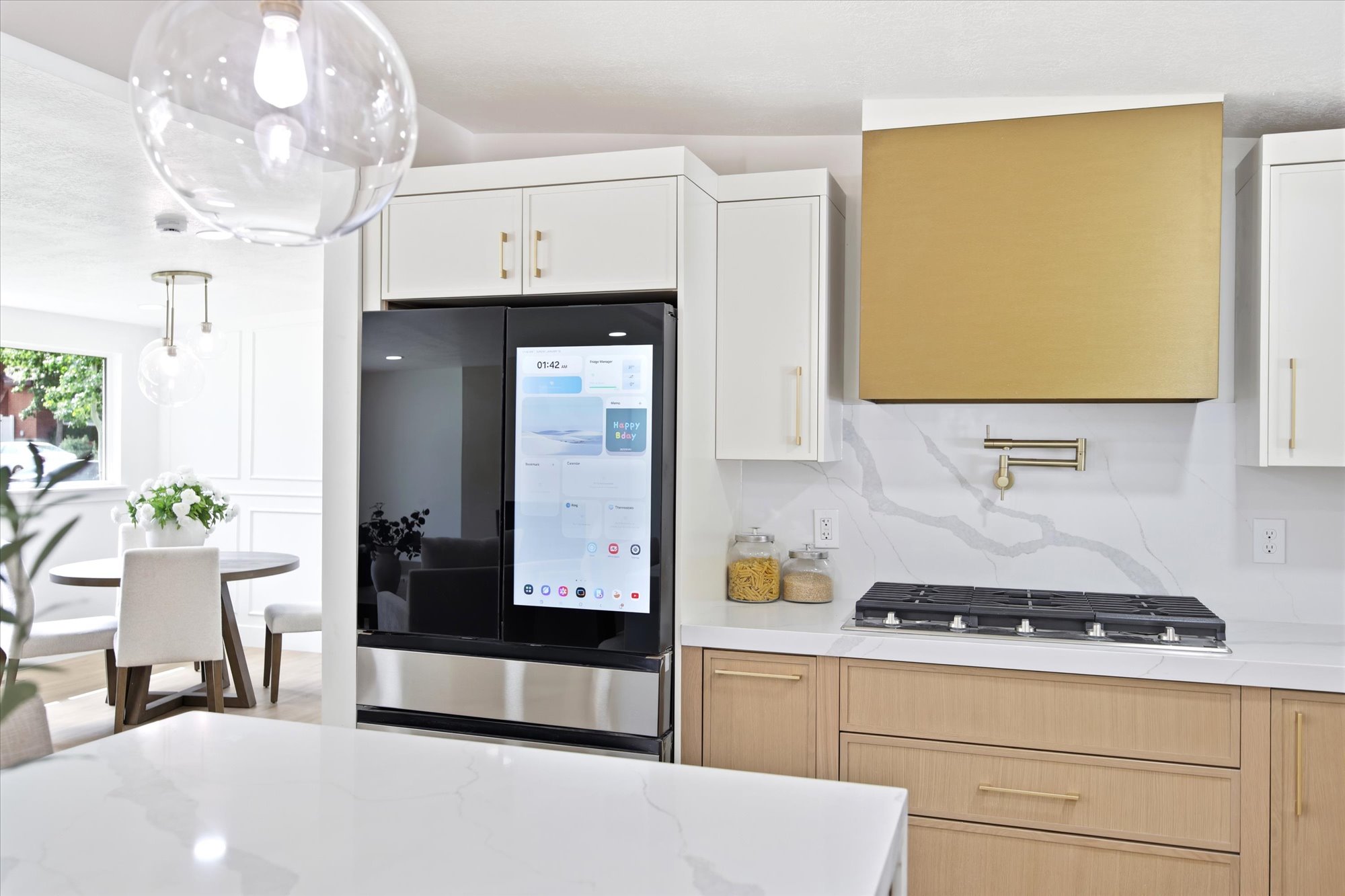 Gourmet kitchen featuring a gold-toned range hood, pot filler, five-burner gas cooktop, and built-in refrigerator