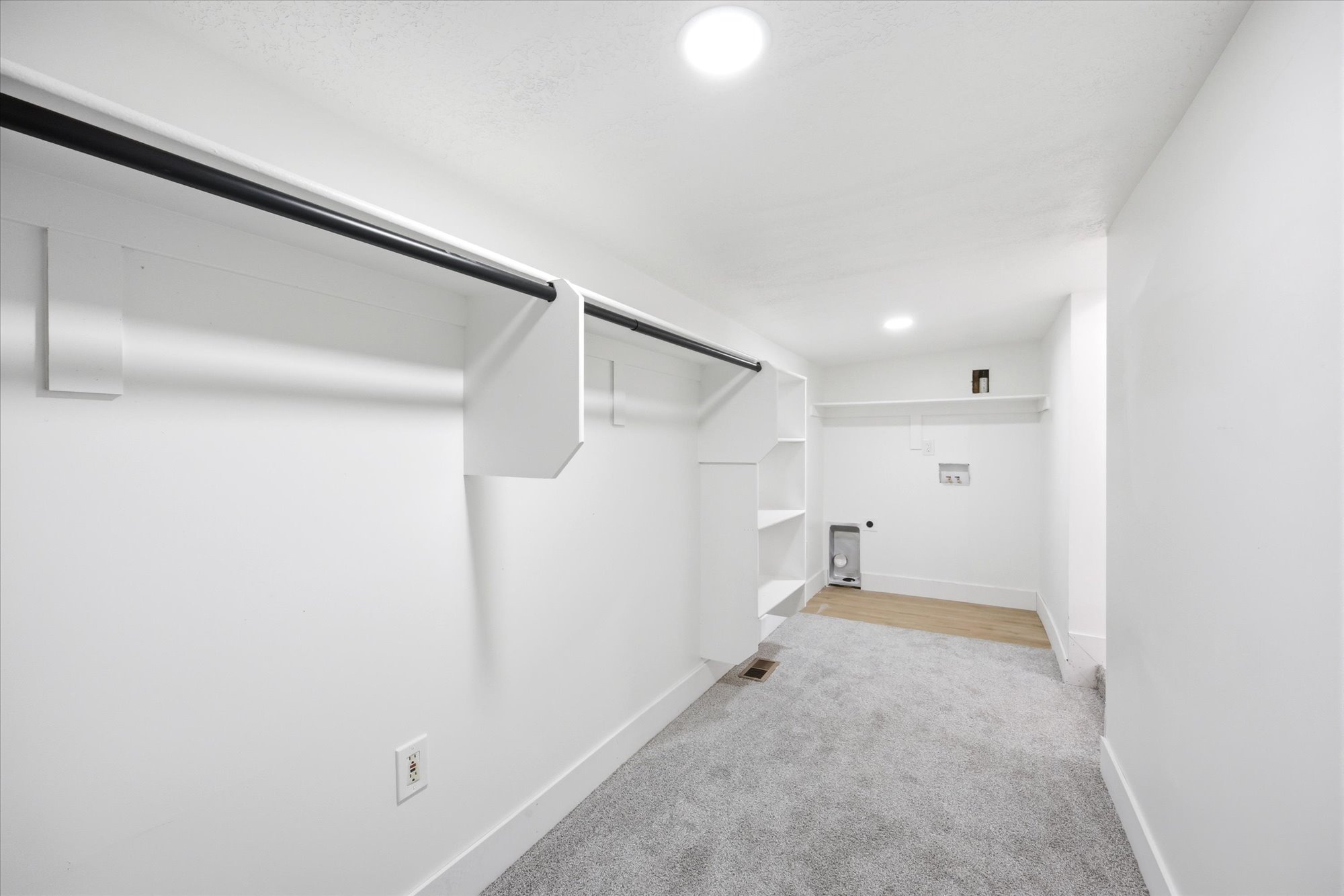 Dedicated laundry area with utility hookups and wood-finish flooring, complemented by built-in shelving