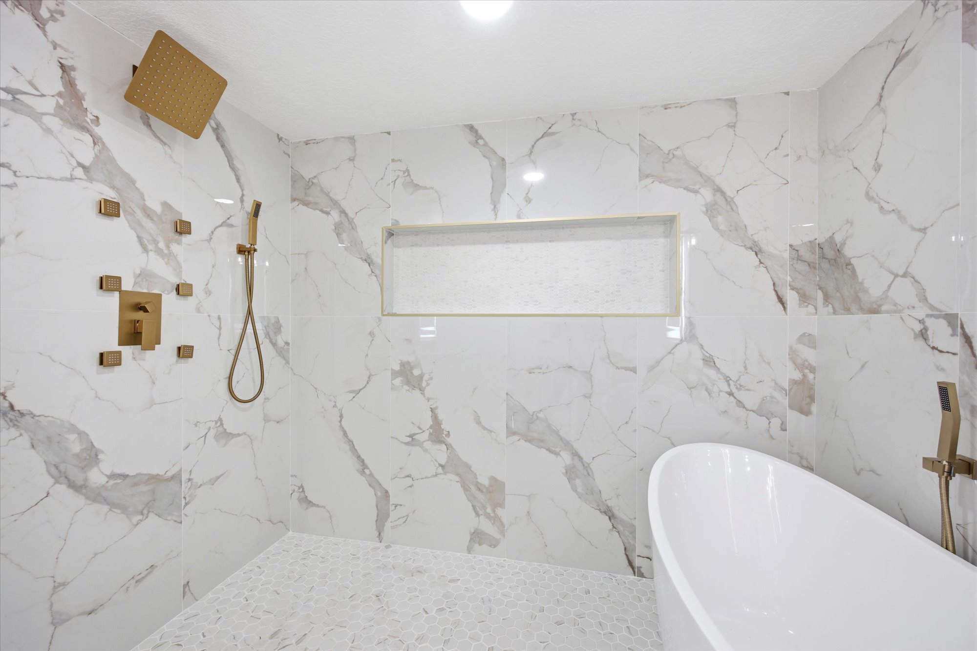 Walk-in shower with gold-tone fixtures, including a rainfall showerhead and handheld sprayer
