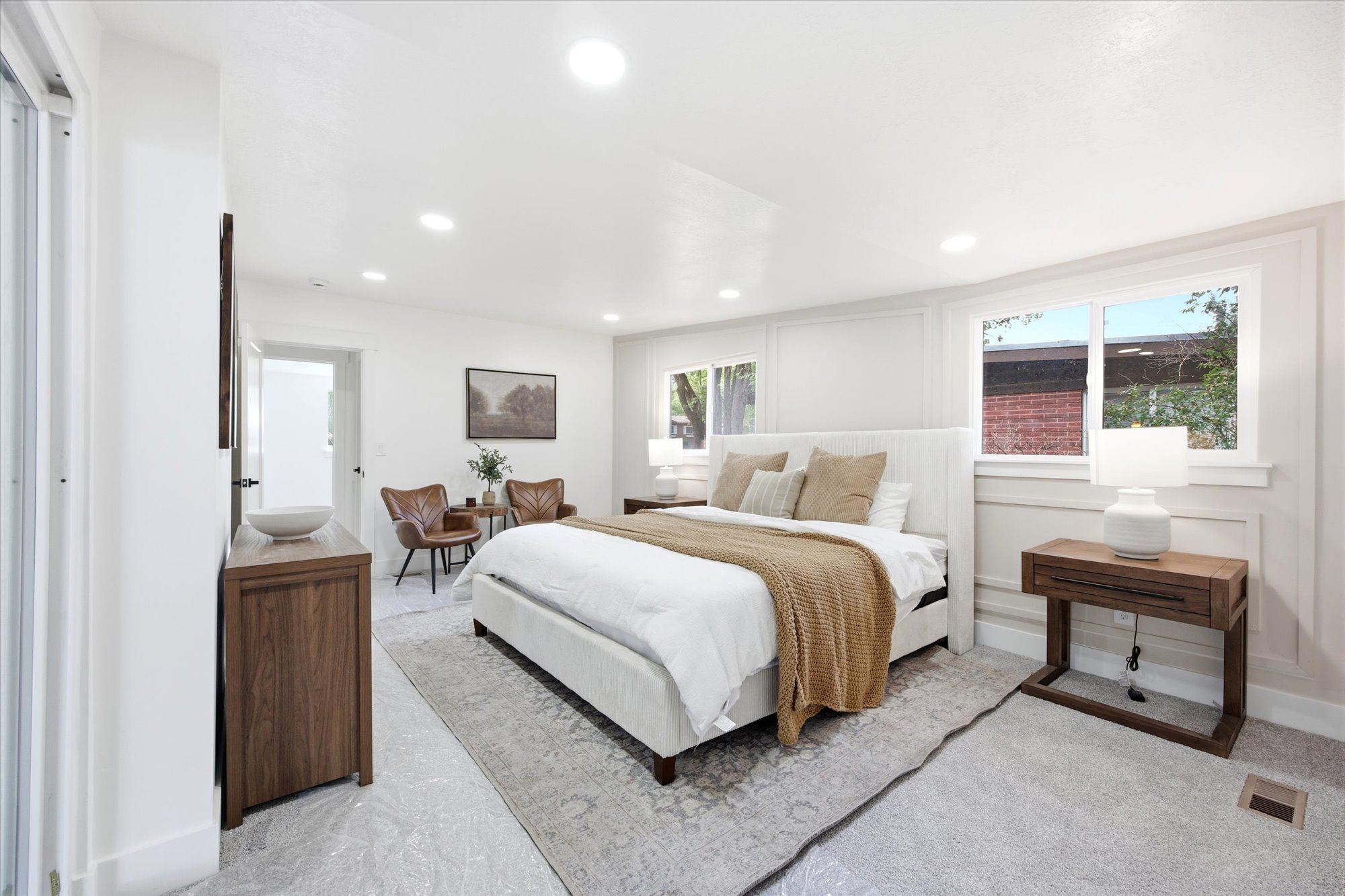 Spacious bedroom featuring large windows, recessed lighting, and white paneled wall accents