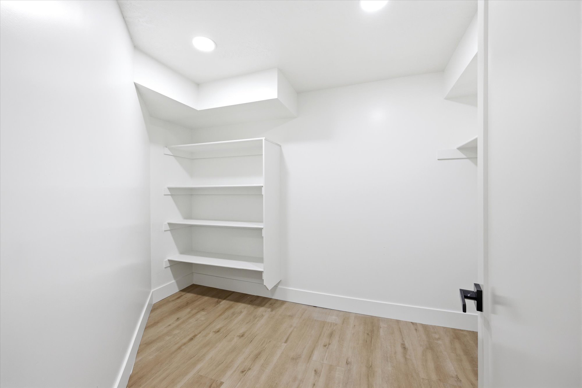 Dedicated storage room featuring wood-finish flooring and recessed lighting
