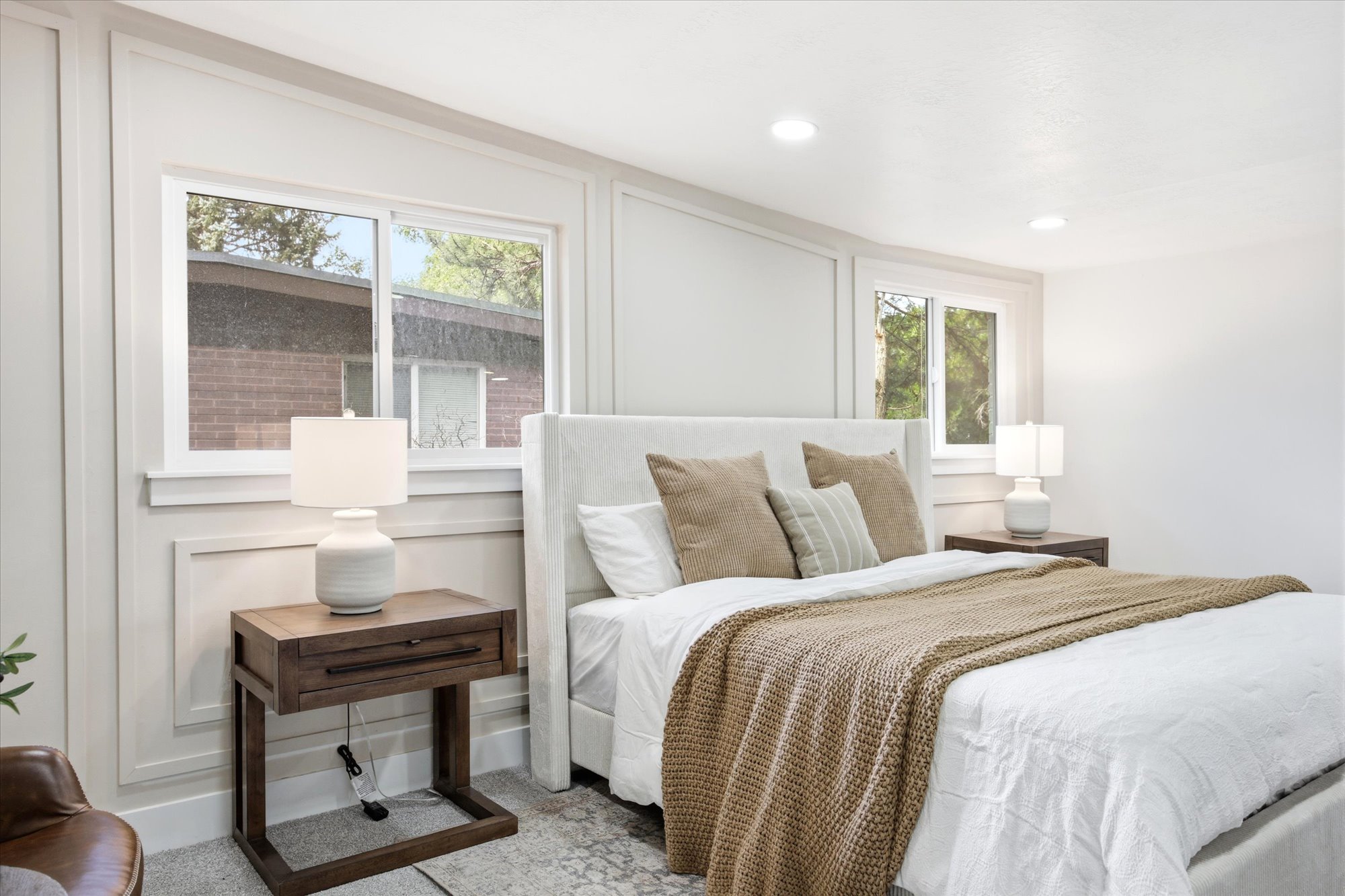 Bright bedroom featuring white paneled walls, recessed lighting, and dual windows