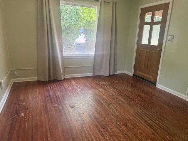 Wood-finish flooring with baseboard molding and wall trim
