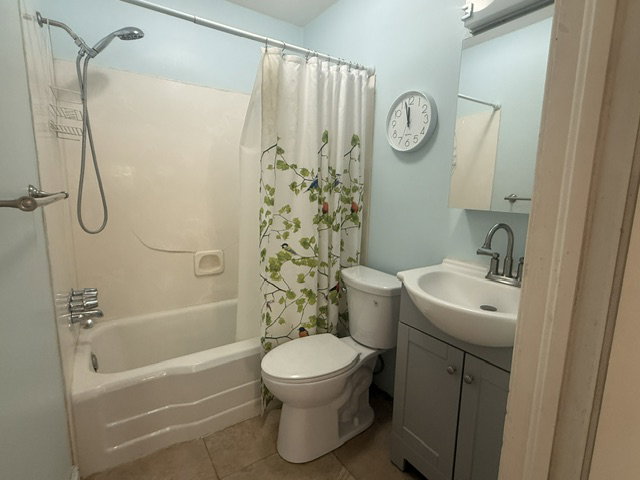 Full bathroom featuring a tub/shower combination with a single-handle faucet, a toilet, a vanity with a white basin and chrome faucet, and a wall-mounted mirror