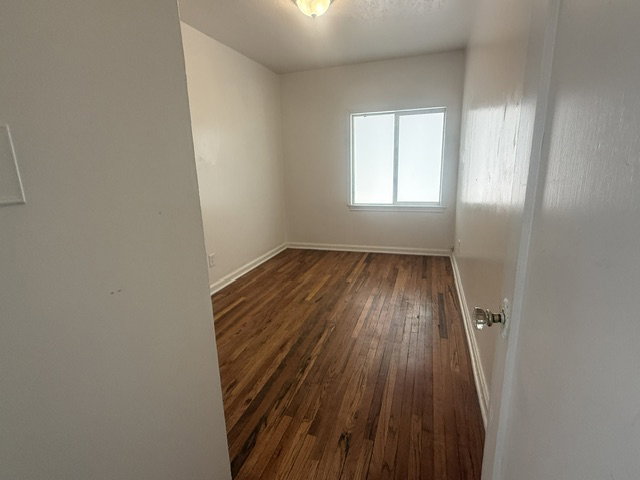 Interior room featuring wood-finish flooring, white baseboards, and neutral wall paint