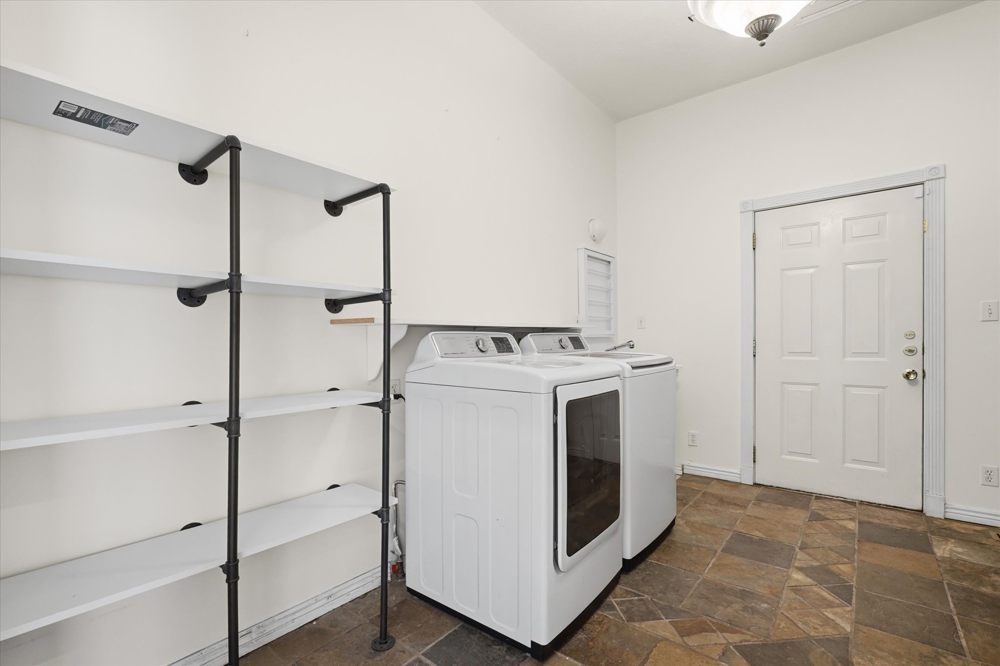 Laundry area featuring slate-look flooring and a white paneled door
