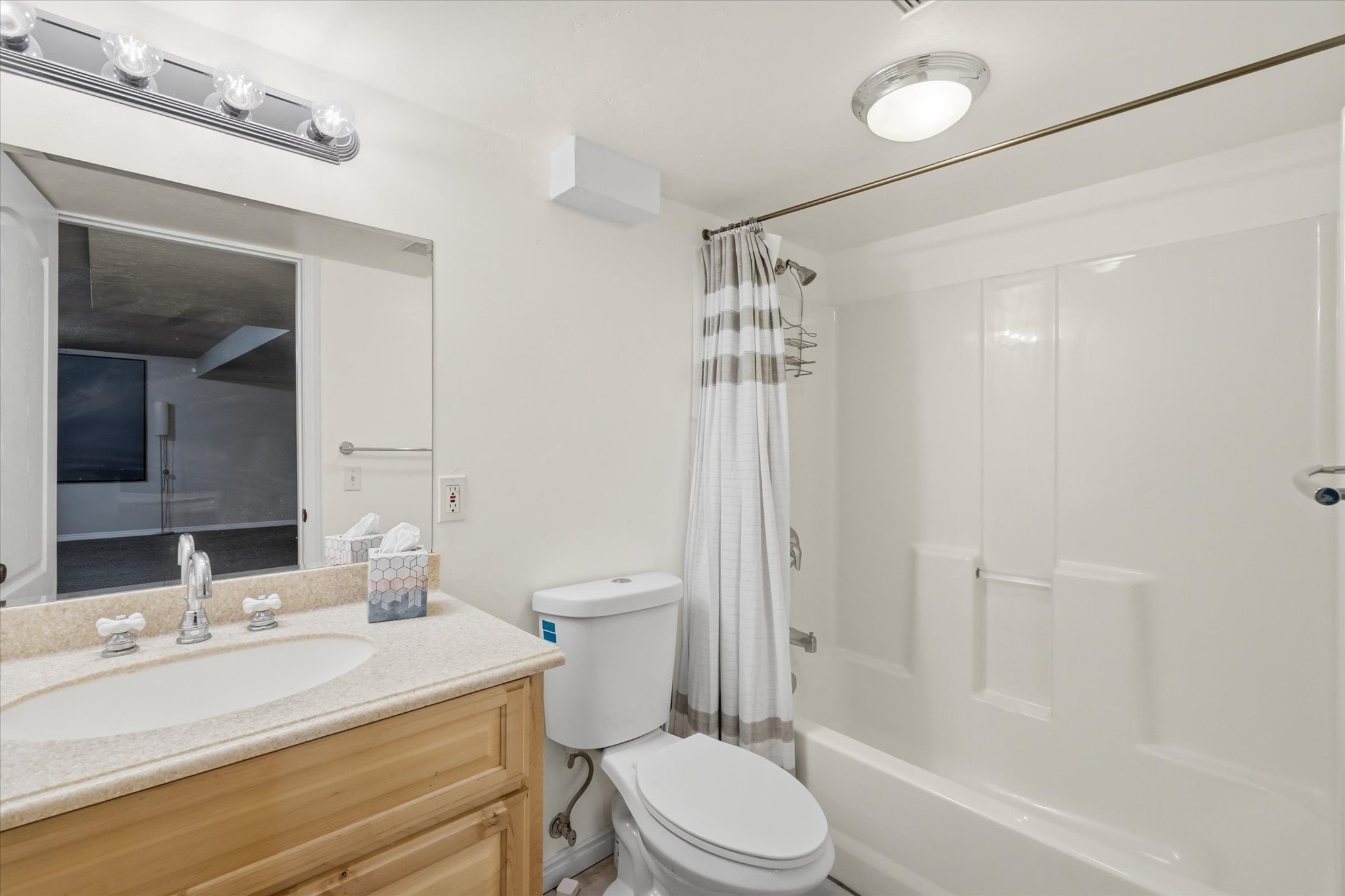 Bathroom featuring a light wood-finish vanity with a stone-finish countertop, undermount sink, and chrome faucet