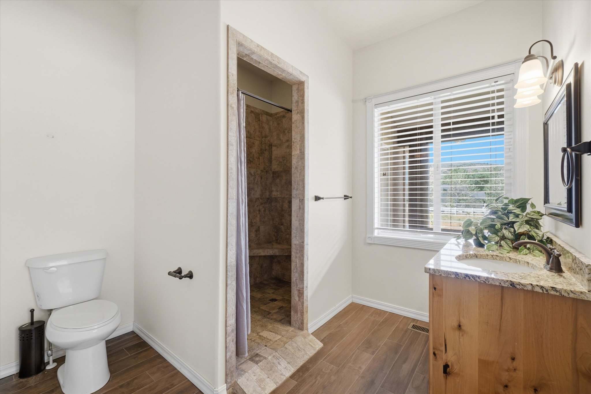 Bathroom featuring wood-finish flooring and a walk-in shower with natural stone tile