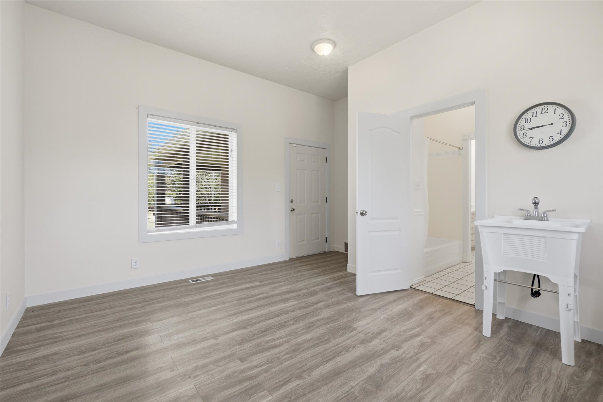 Bright room featuring wood-finish flooring, a utility sink, and a window with blinds