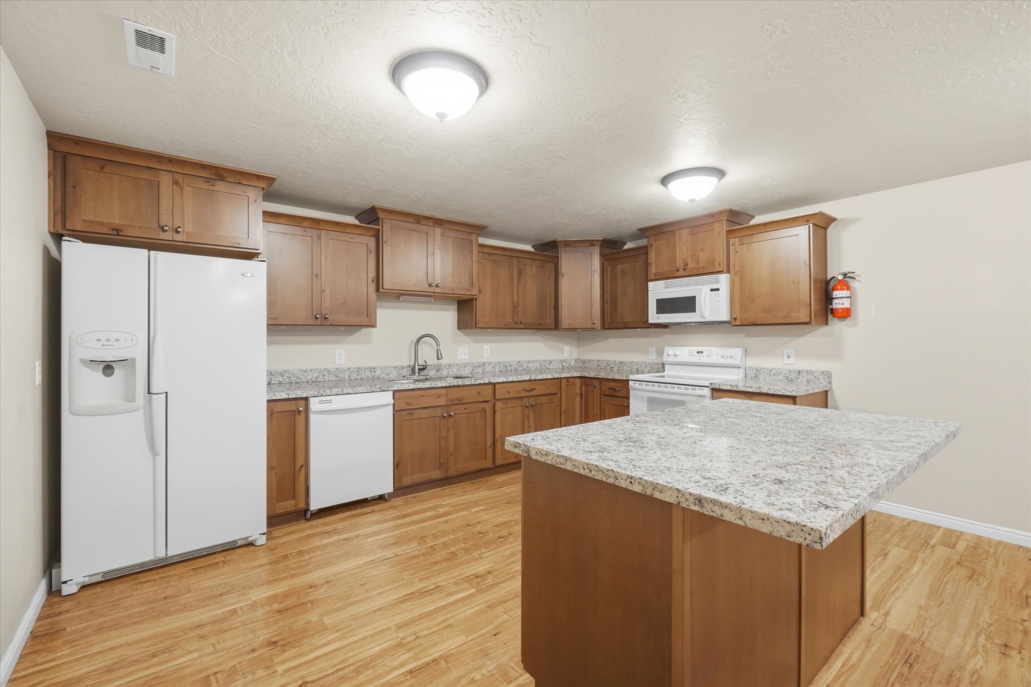 Kitchen featuring wood-finish cabinetry, light-toned countertops, and wood-finish flooring