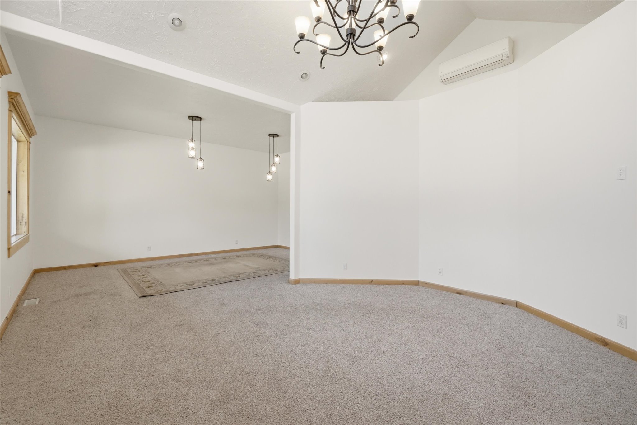 Spacious interior featuring vaulted ceilings and neutral carpeting