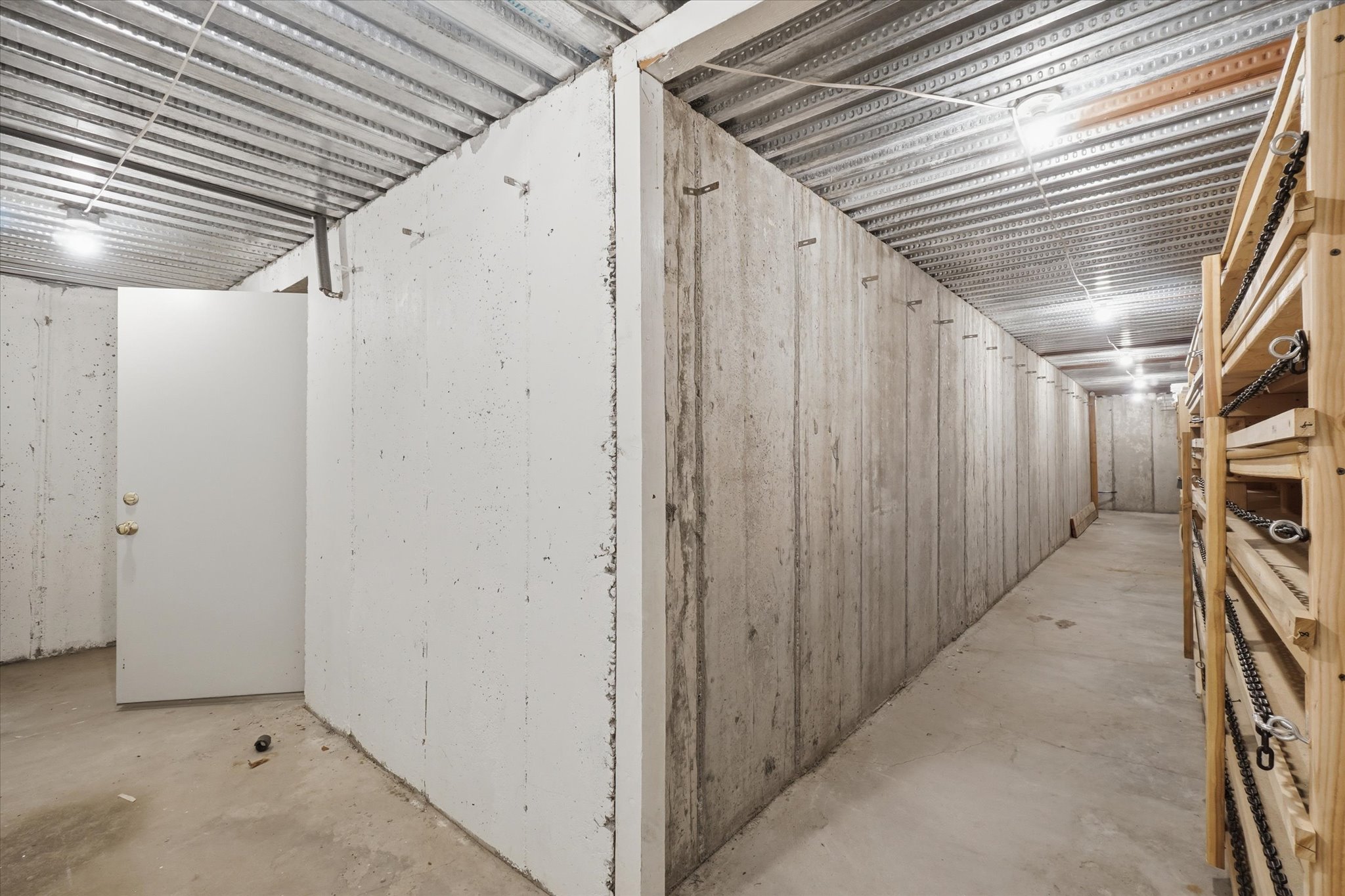 Corrugated metal ceiling with exposed joists, concrete flooring, and exposed concrete walls