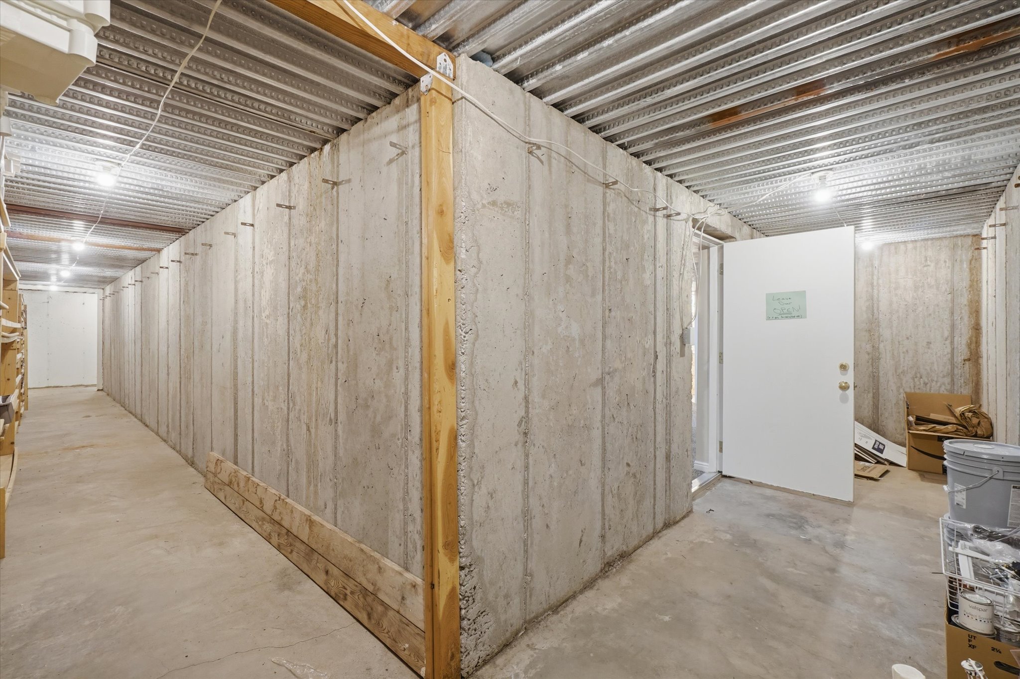Spacious concrete-walled area featuring exposed ceiling joists and integrated lighting