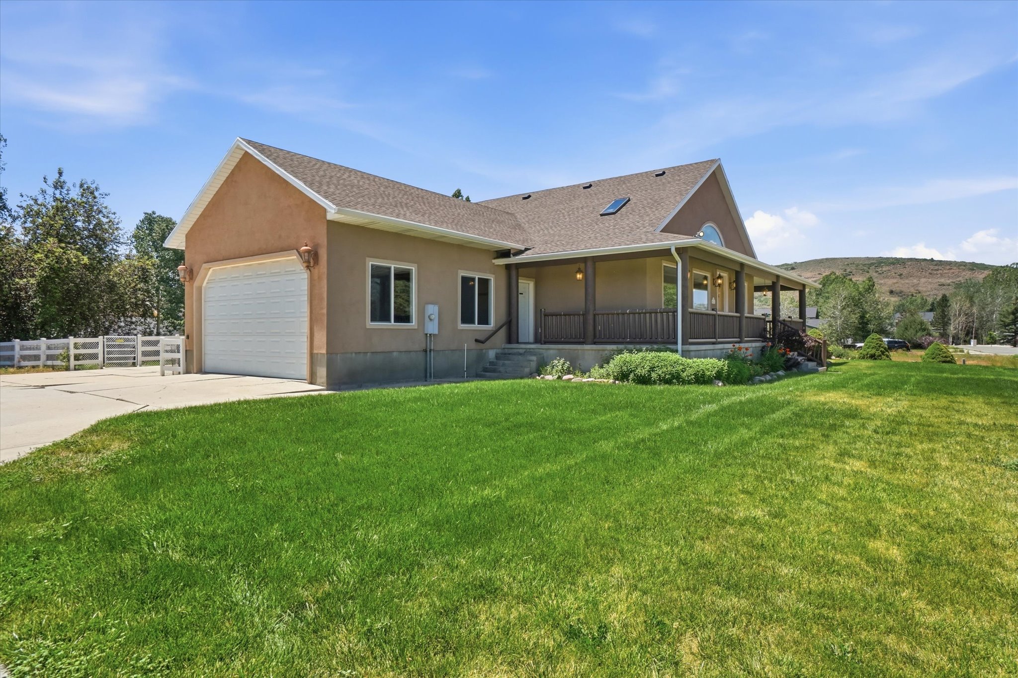 Stucco exterior residence featuring an attached garage, a covered front porch, and a dormer window