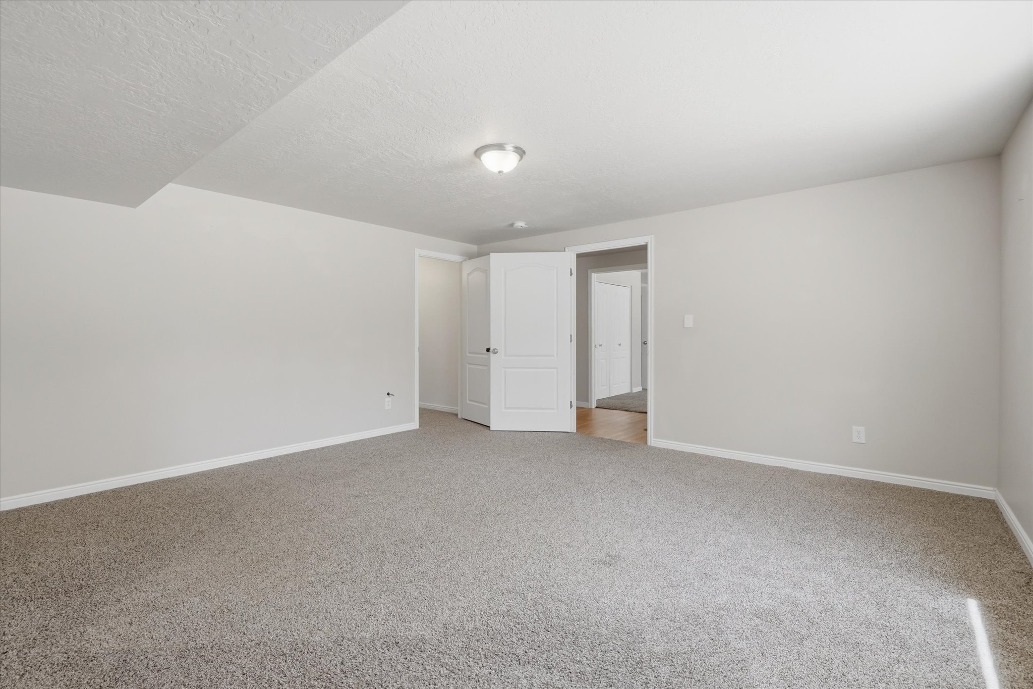 Spacious room featuring neutral carpeting, light-colored walls, white trim, and a semi-flush mount ceiling light